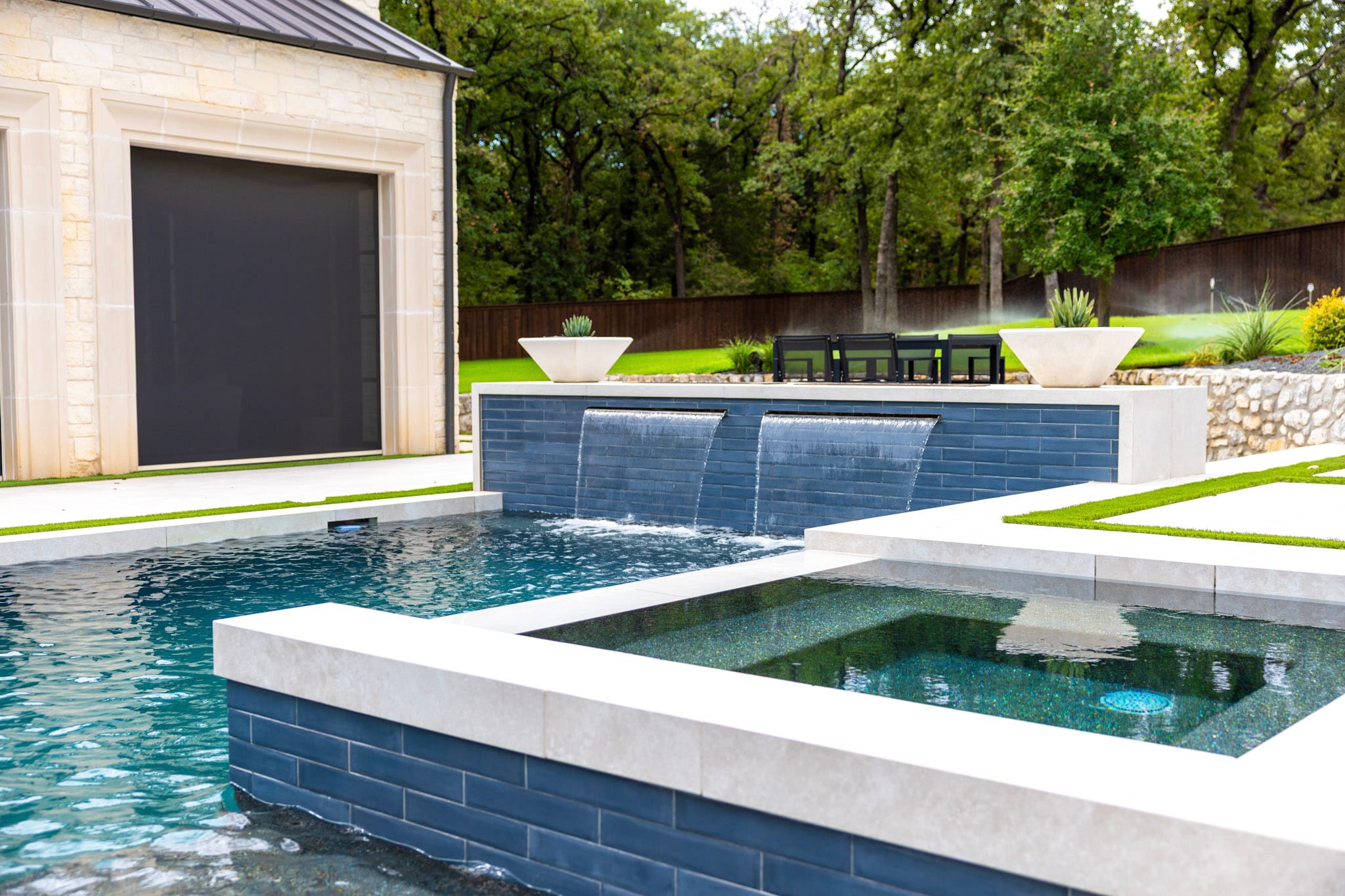 Raised spa in foreground with twin waterfalls flowing into pool