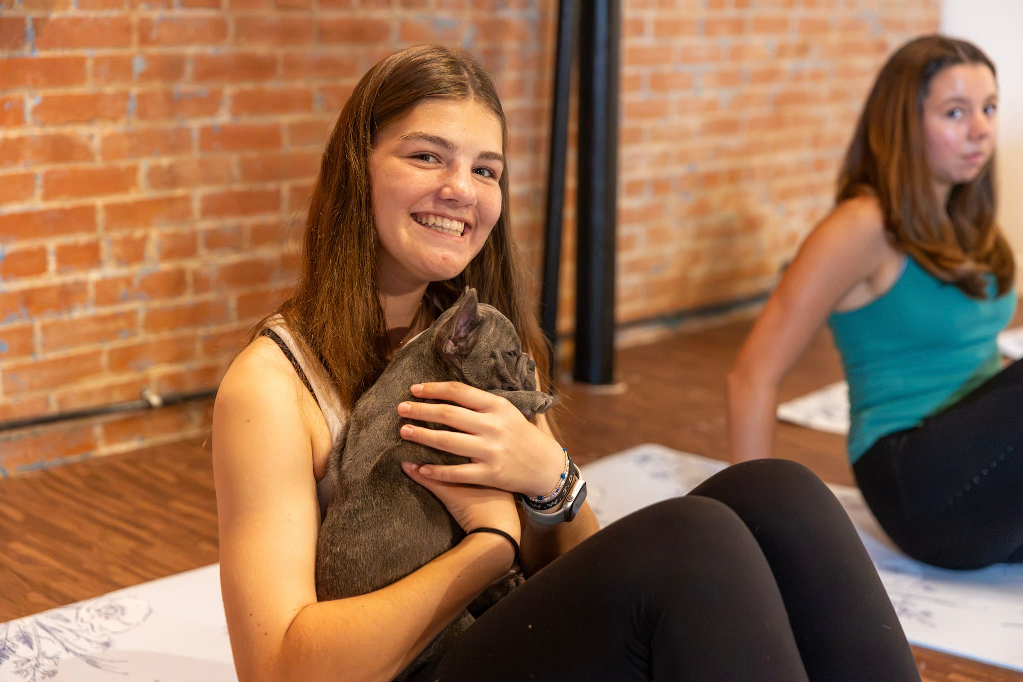 Teen participant smiling while holding a gray French bulldog puppy