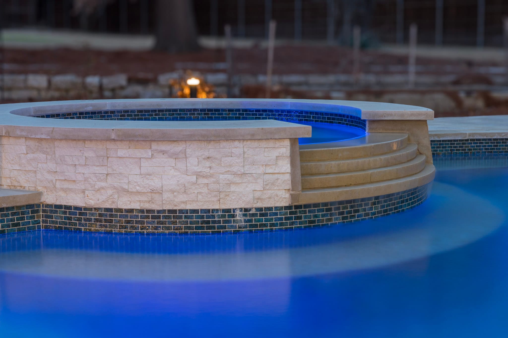 Raised circular spa with blue lighting and curved spillway steps