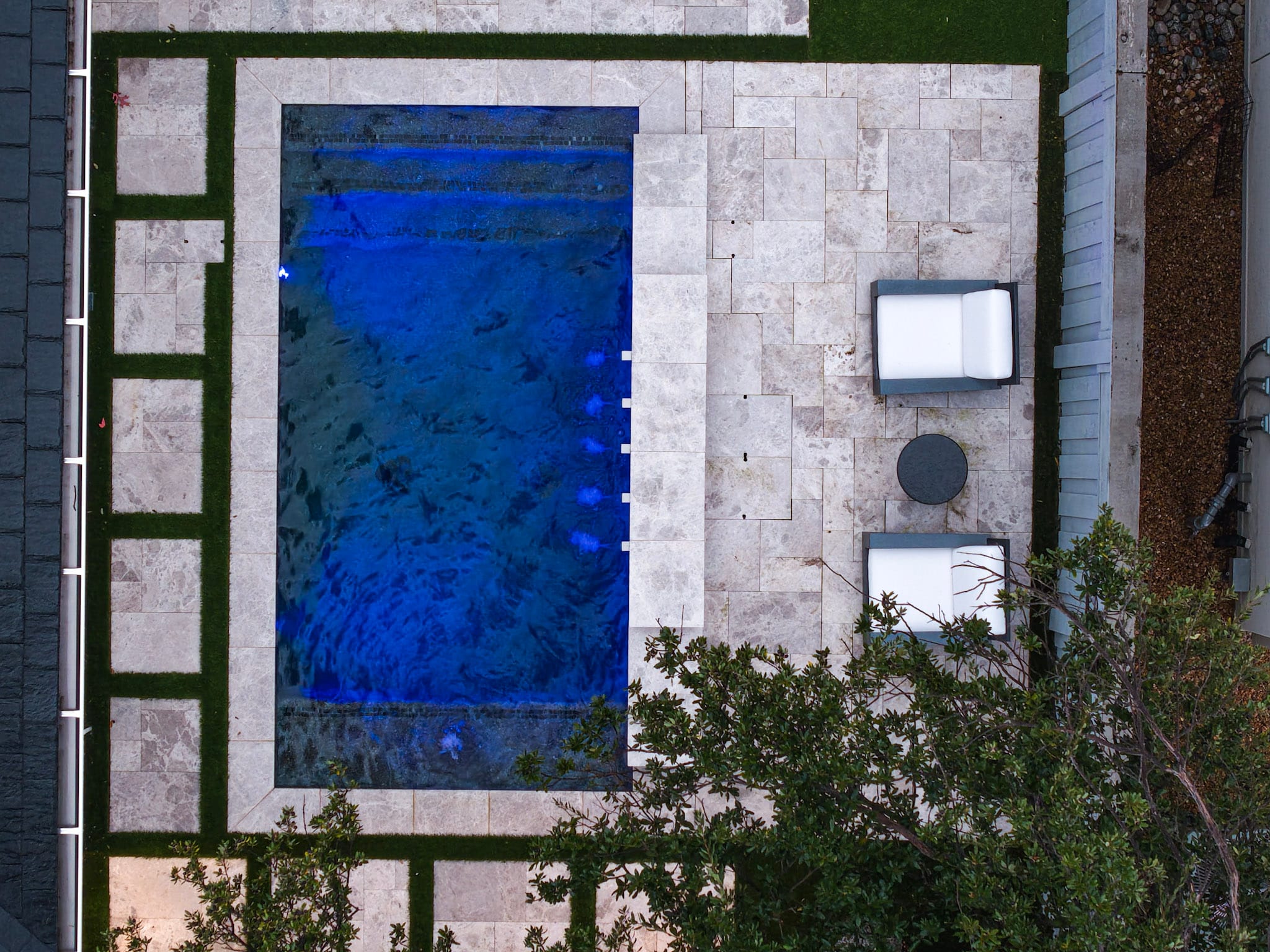 Aerial view of rectangular pool with patio seating and turf accents