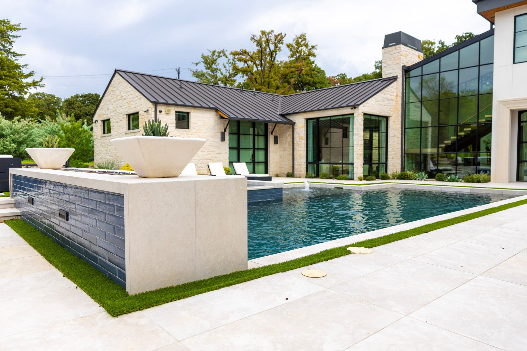 Southlake swimming pool beside modern stone home with large windows