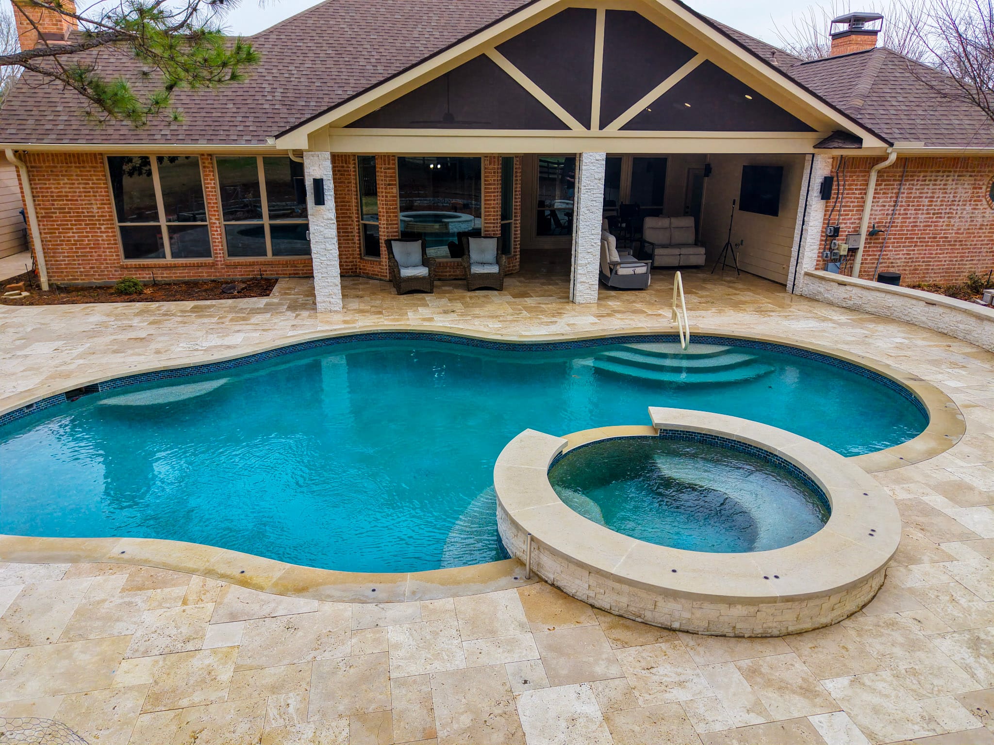Elevated view of remodeled pool, raised spa, travertine deck, and covered patio