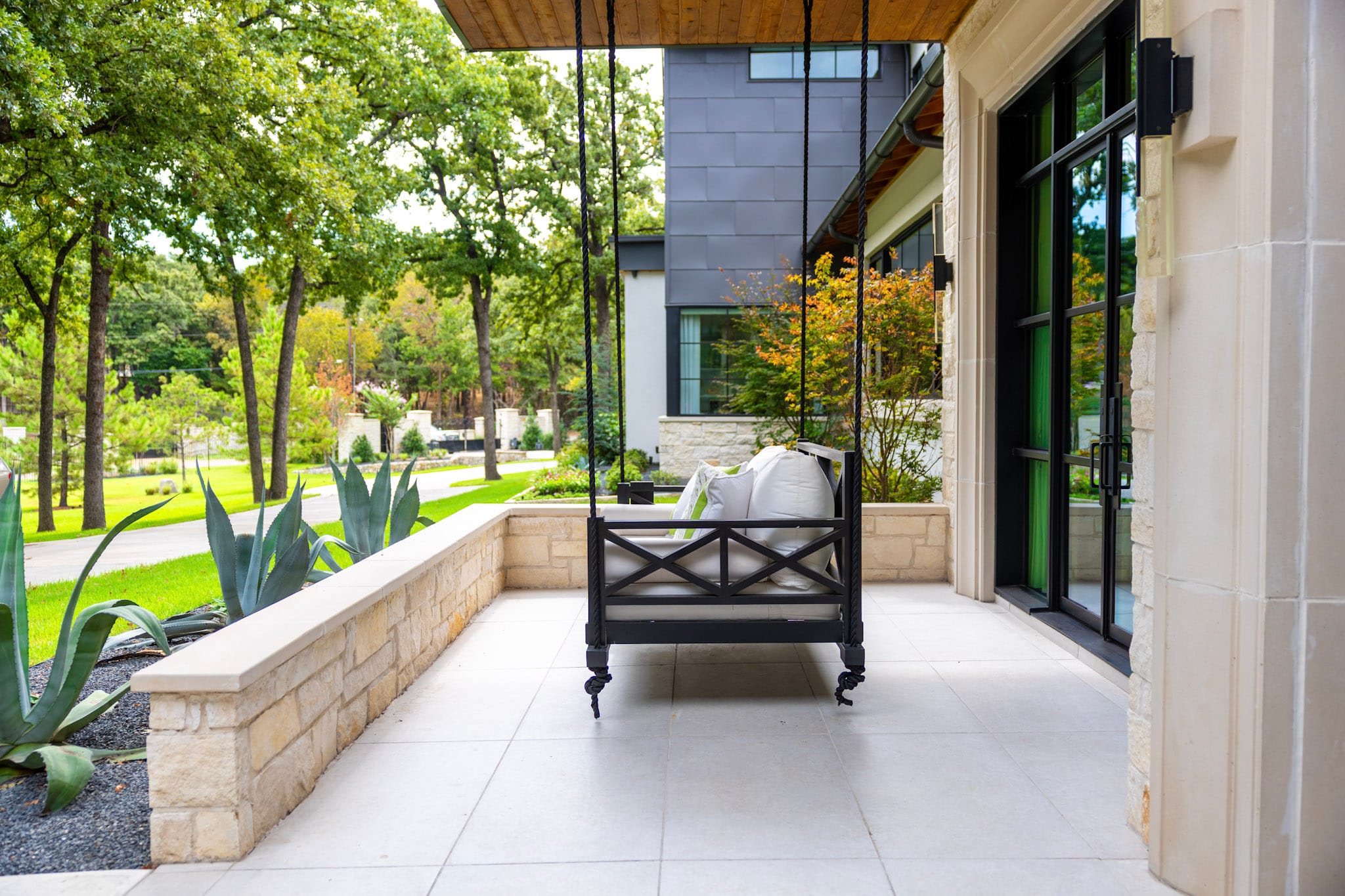Covered front porch with swing, porcelain pavers and stone walls