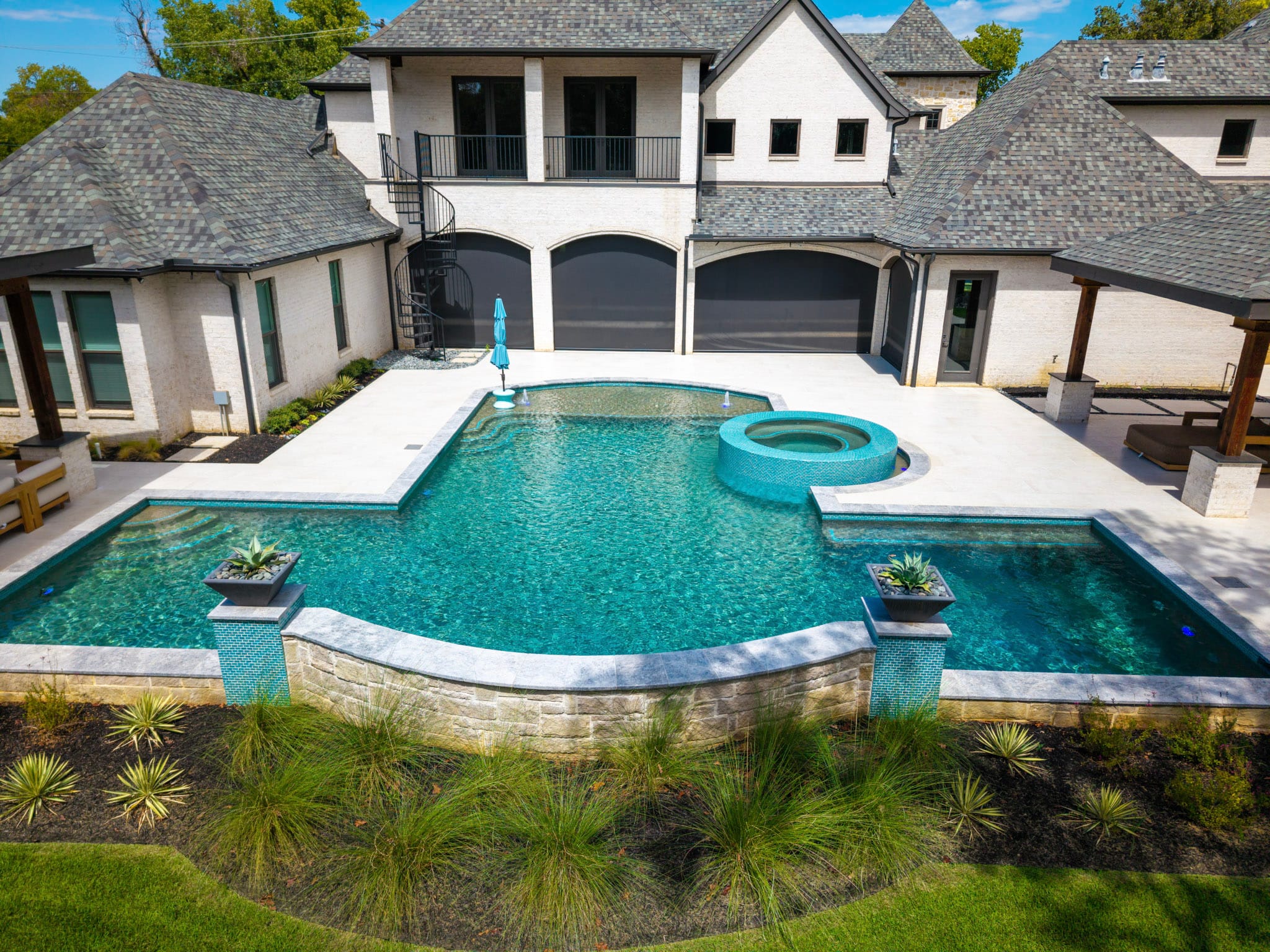 Aerial view of large swimming pool with circular spa, shallow ledge and covered patio