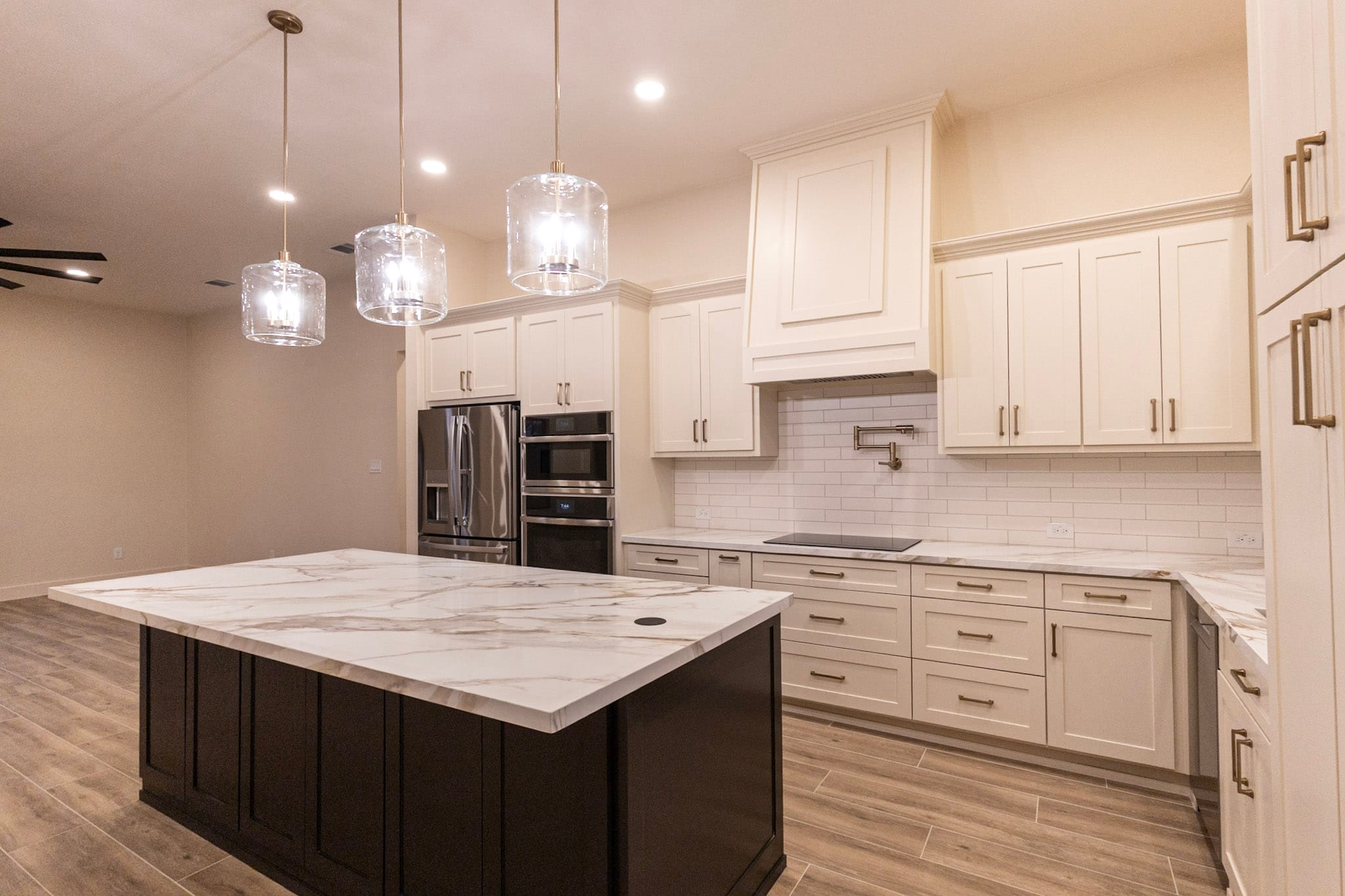 Wide barndominium kitchen with dark island, white cabinets, and stainless appliances