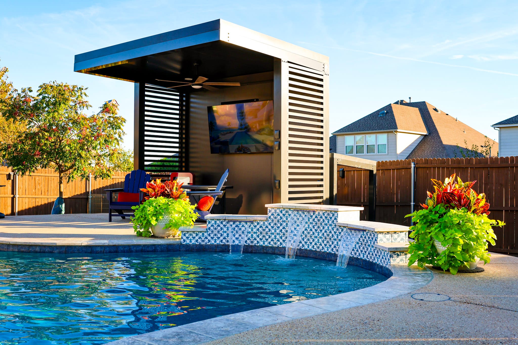 Patterned pool wall with three spillways beside a covered outdoor seating area