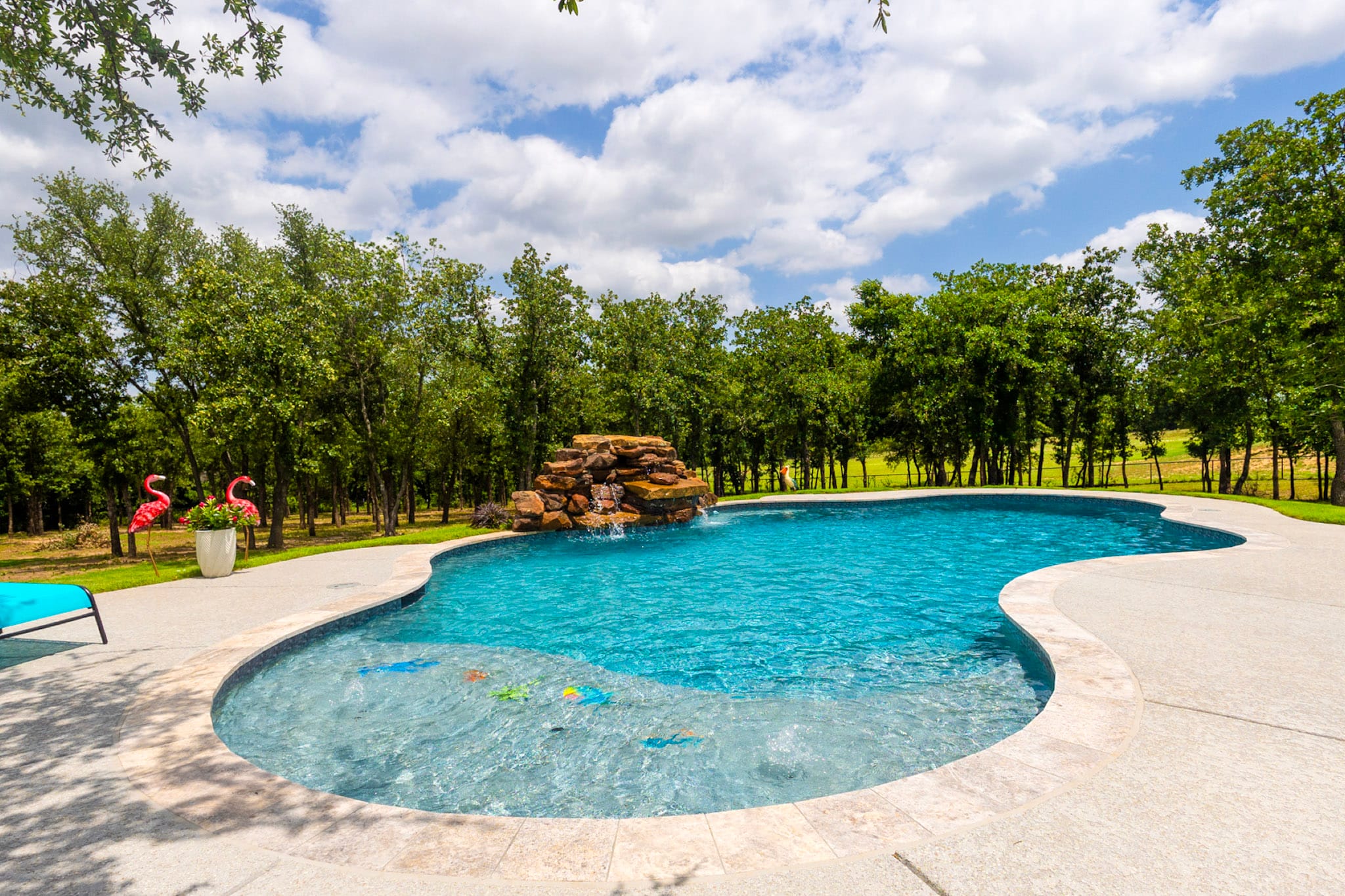 Wide freeform pool with rock waterfall and shallow water area