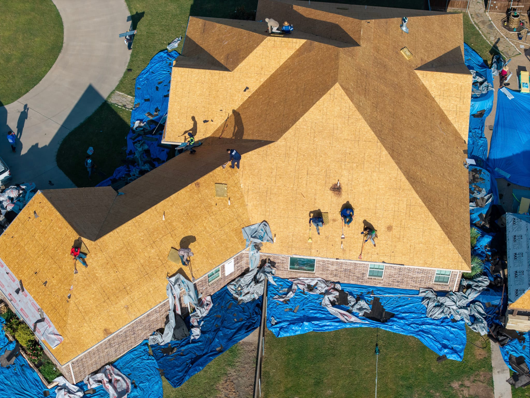 Roofing crew working across exposed roof decking on Leonard Texas home