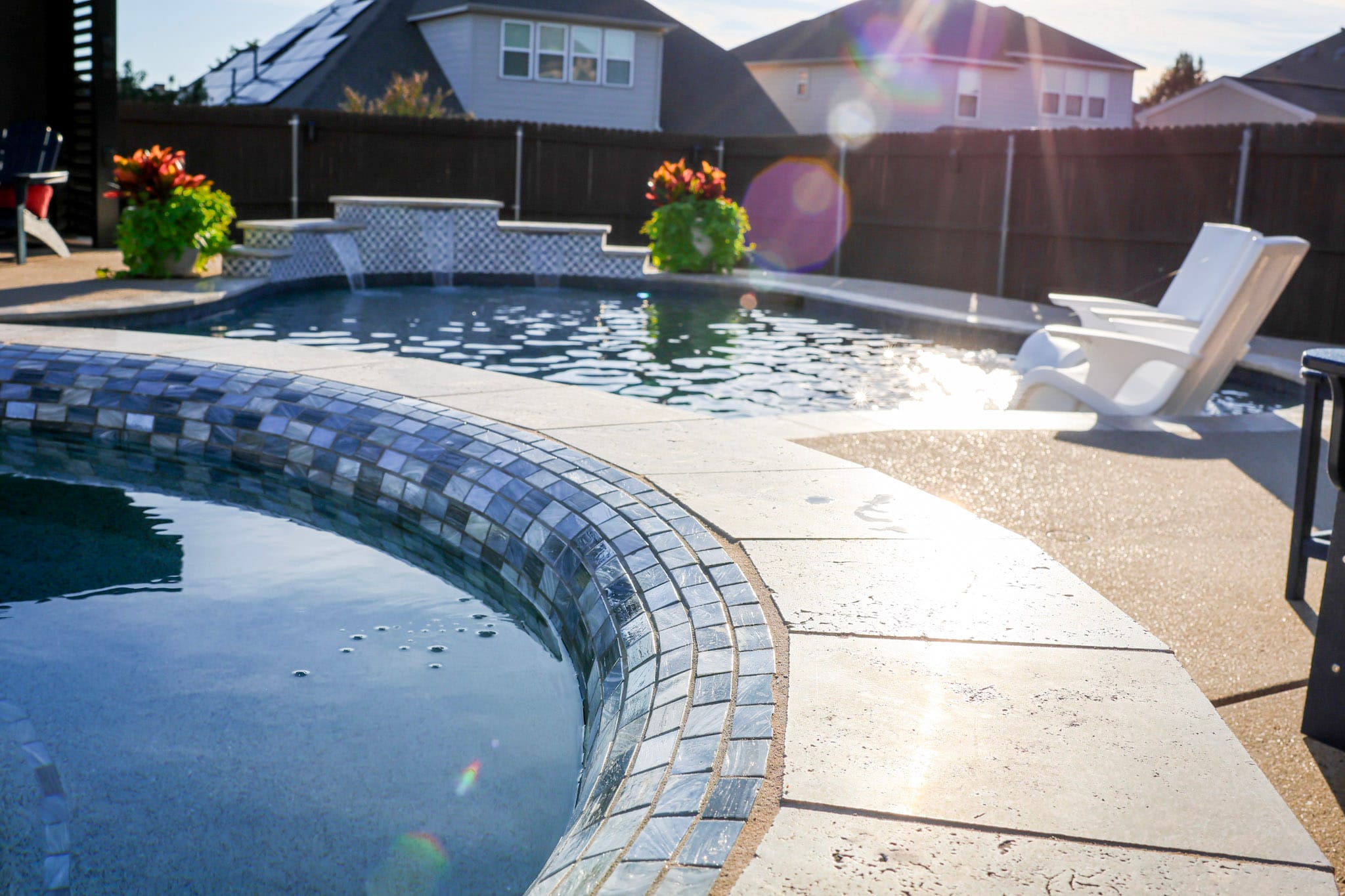 Curved raised spa with freeform pool and water features in background