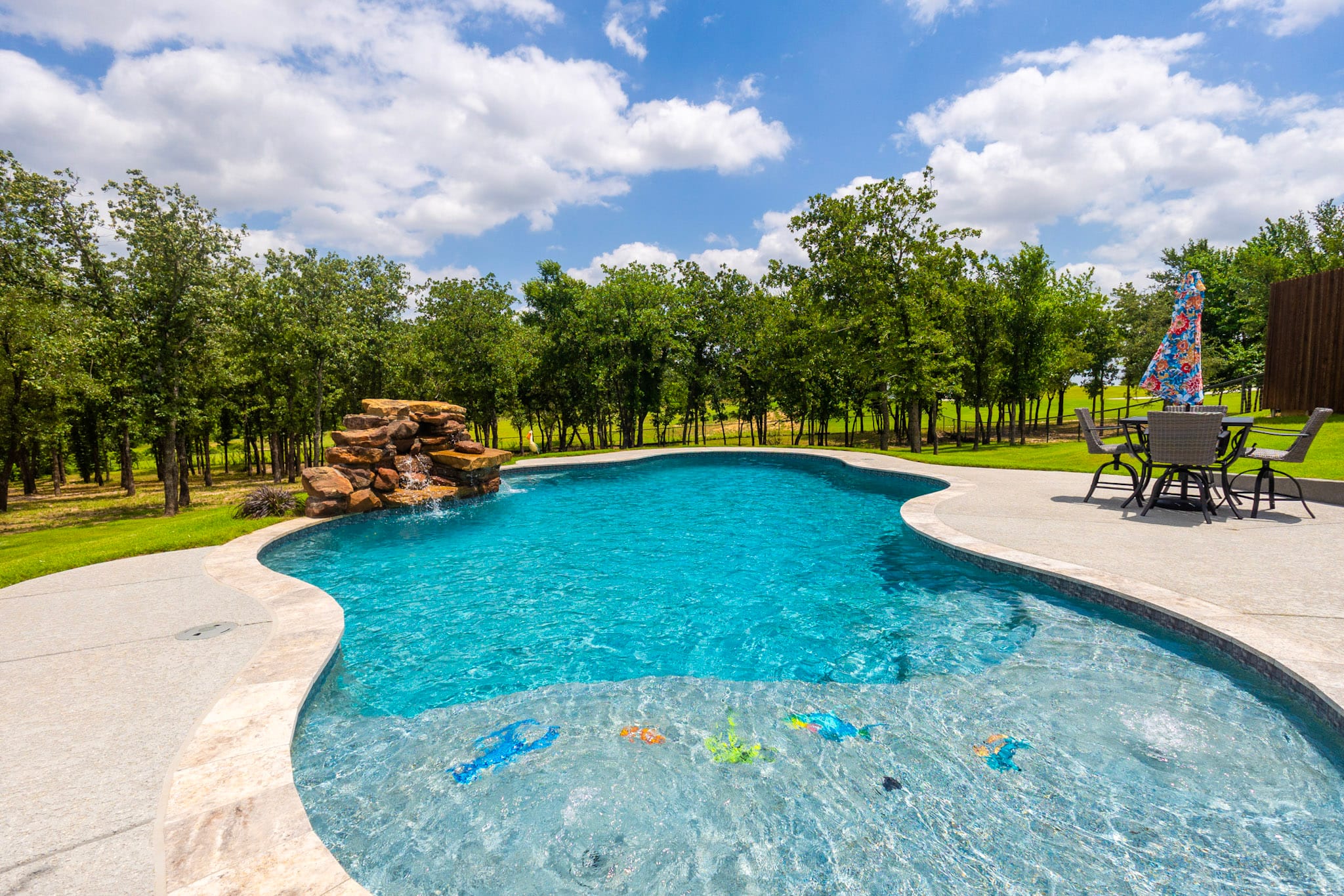 Shallow pool shelf leading into freeform swimming pool with waterfall
