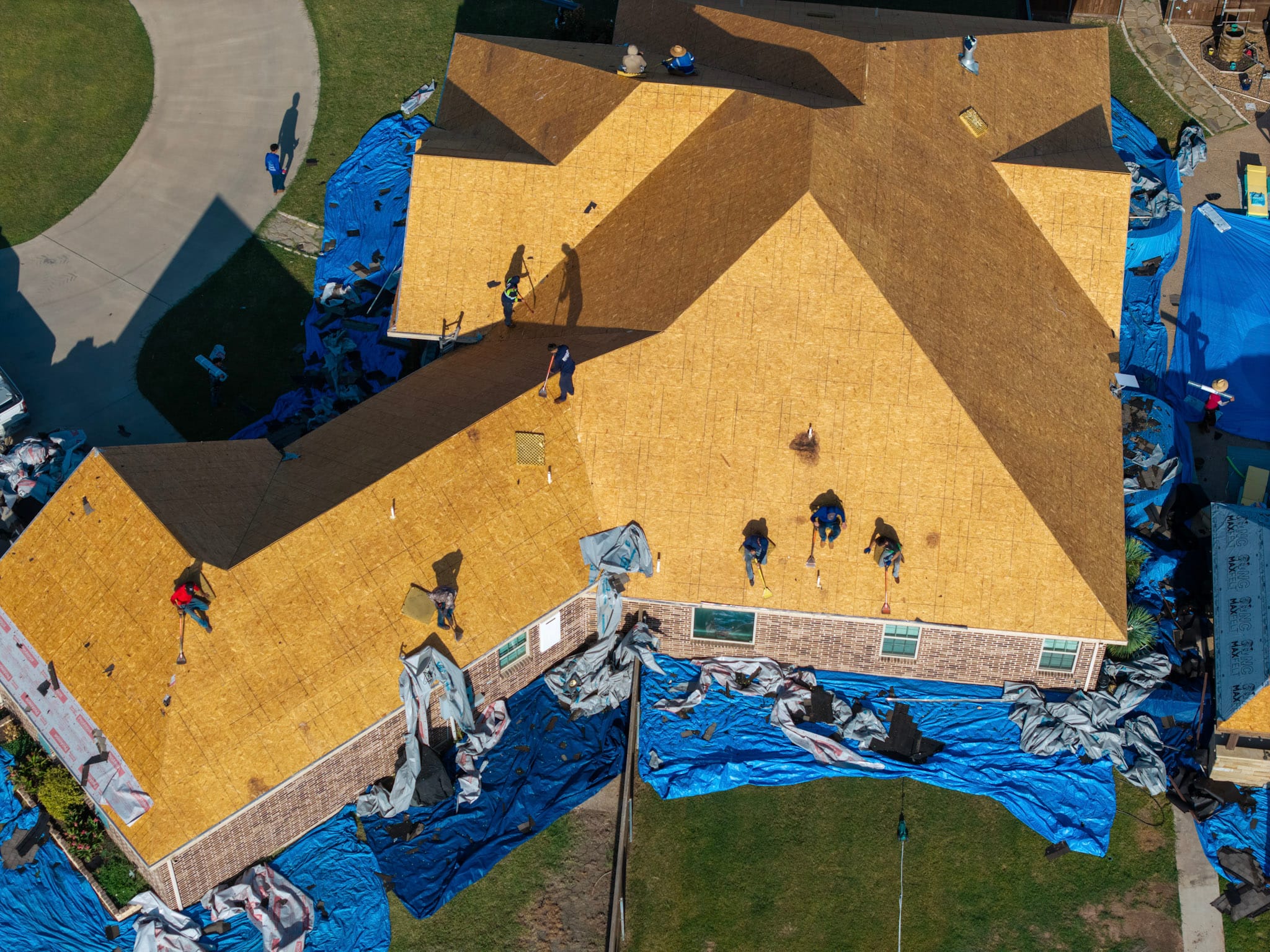 Workers preparing exposed roof decking on residential home in Leonard