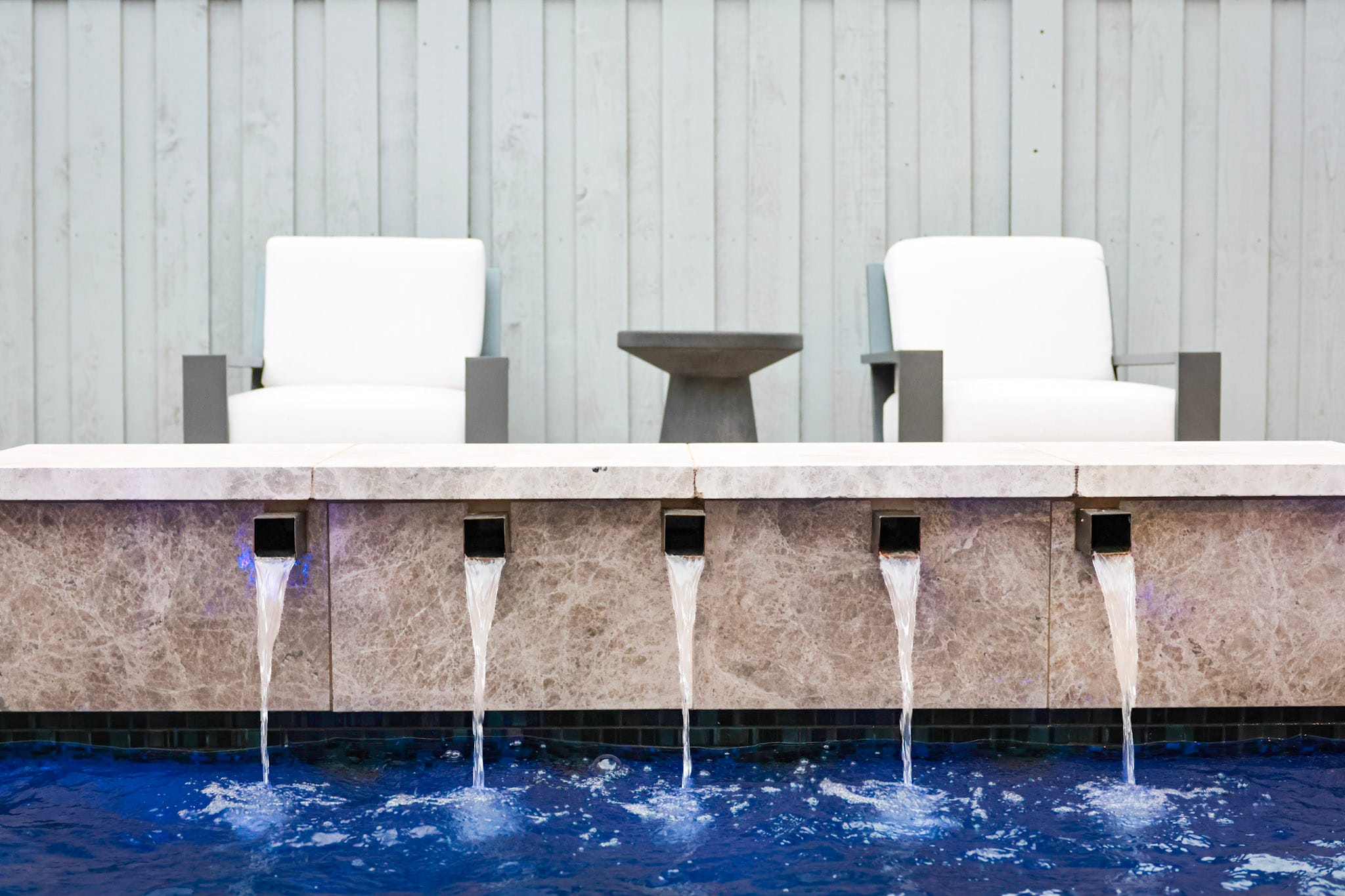 Linear outdoor fireplace framed by white seating and dark wall panels