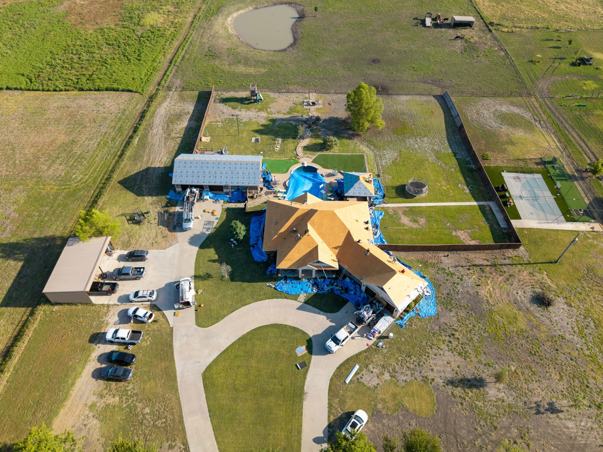 Roofers working on exposed decking above stone home in Leonard Texas