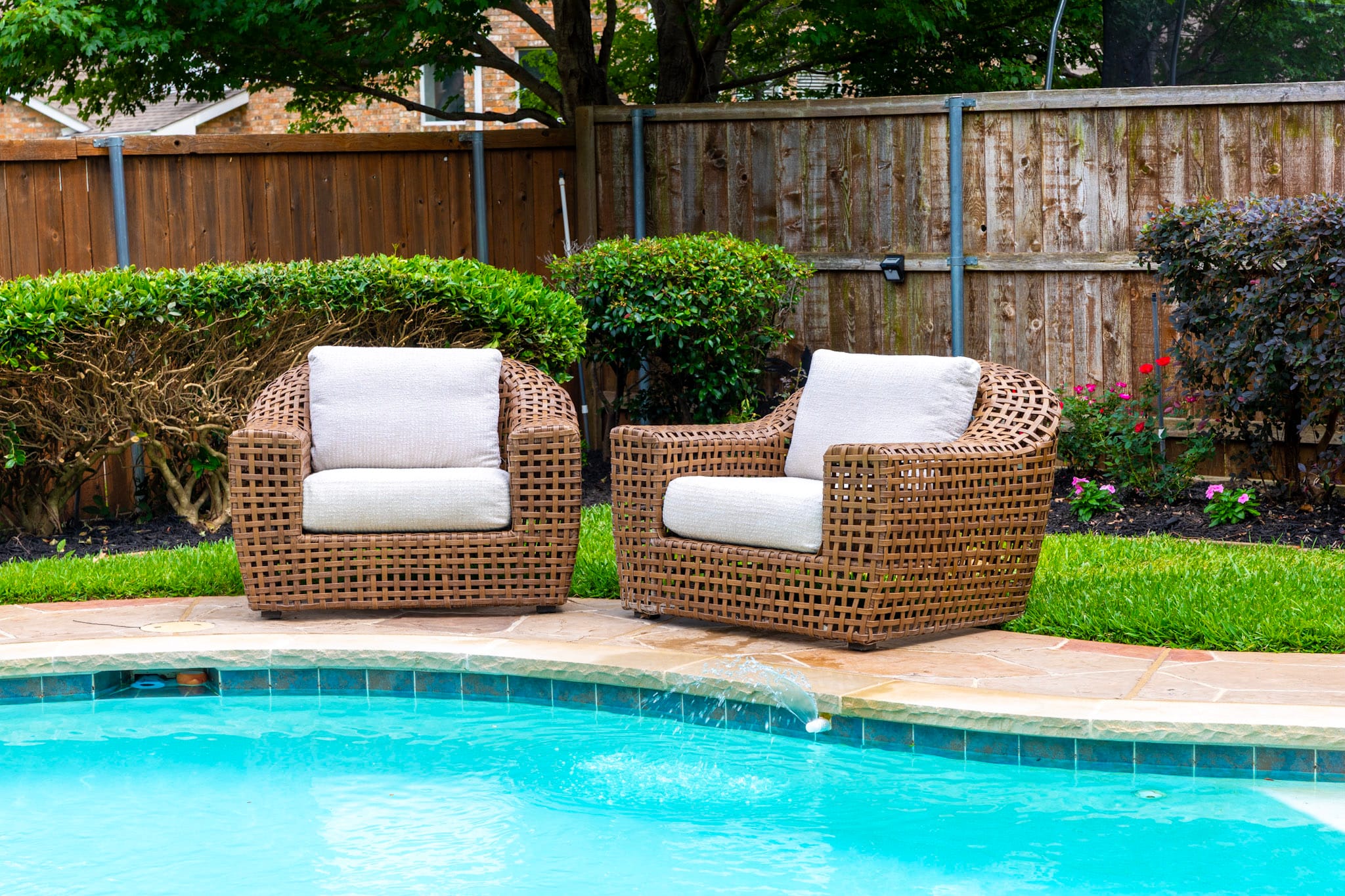 Two woven lounge chairs positioned beside a freeform pool