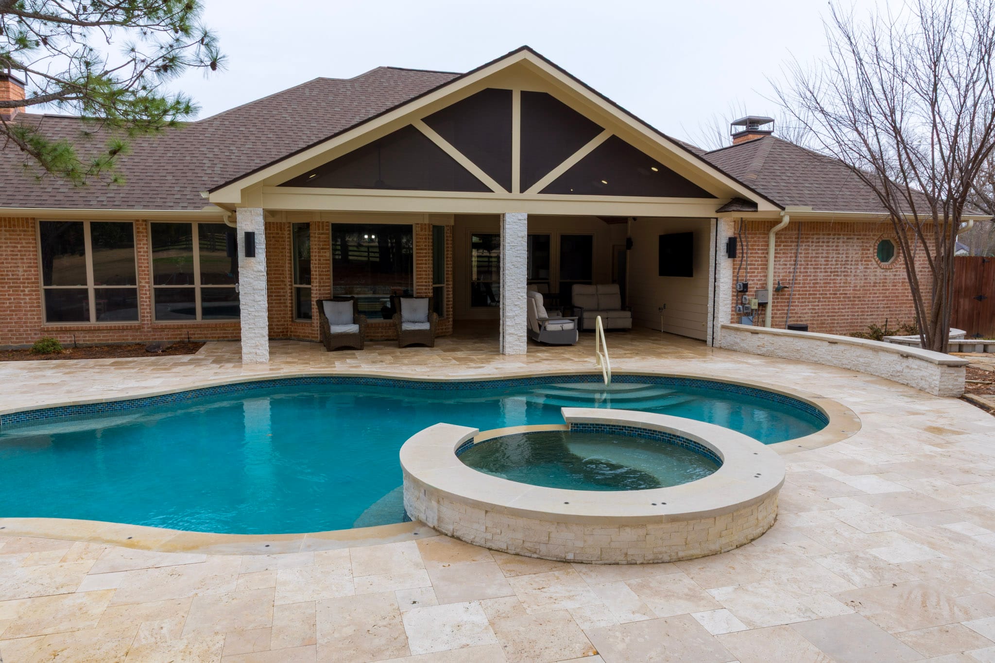 Remodeled pool and raised spa facing a covered backyard patio