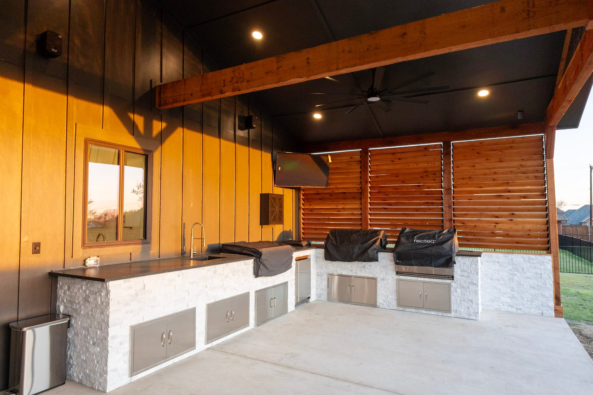 Covered outdoor kitchen with timber beams and built-in stainless storage