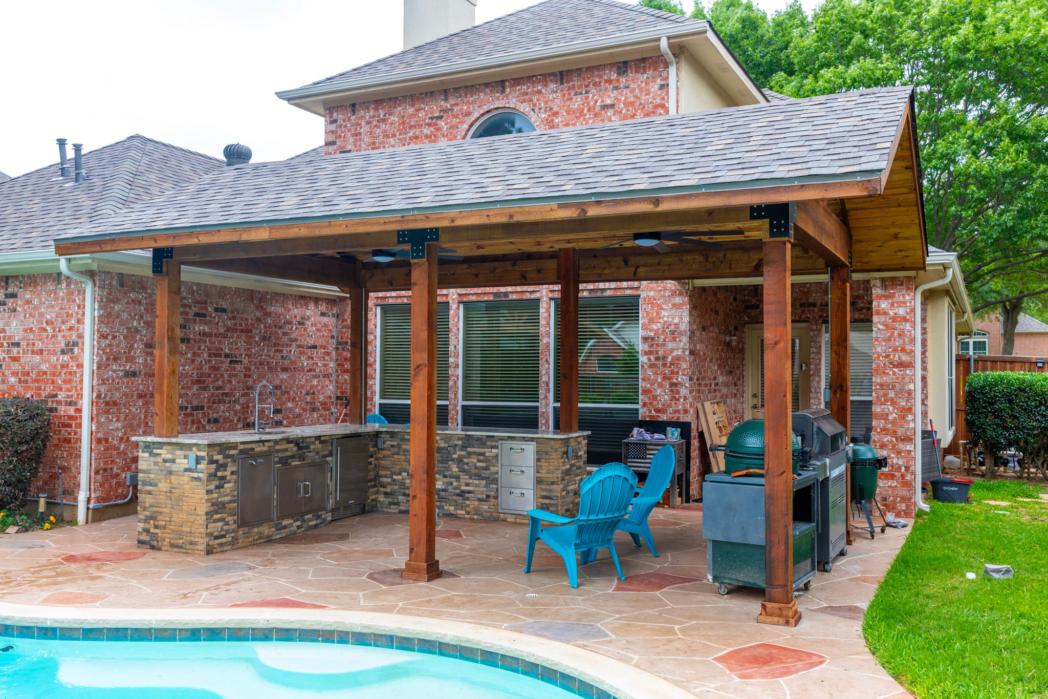 Covered outdoor kitchen with stone veneer and stainless storage