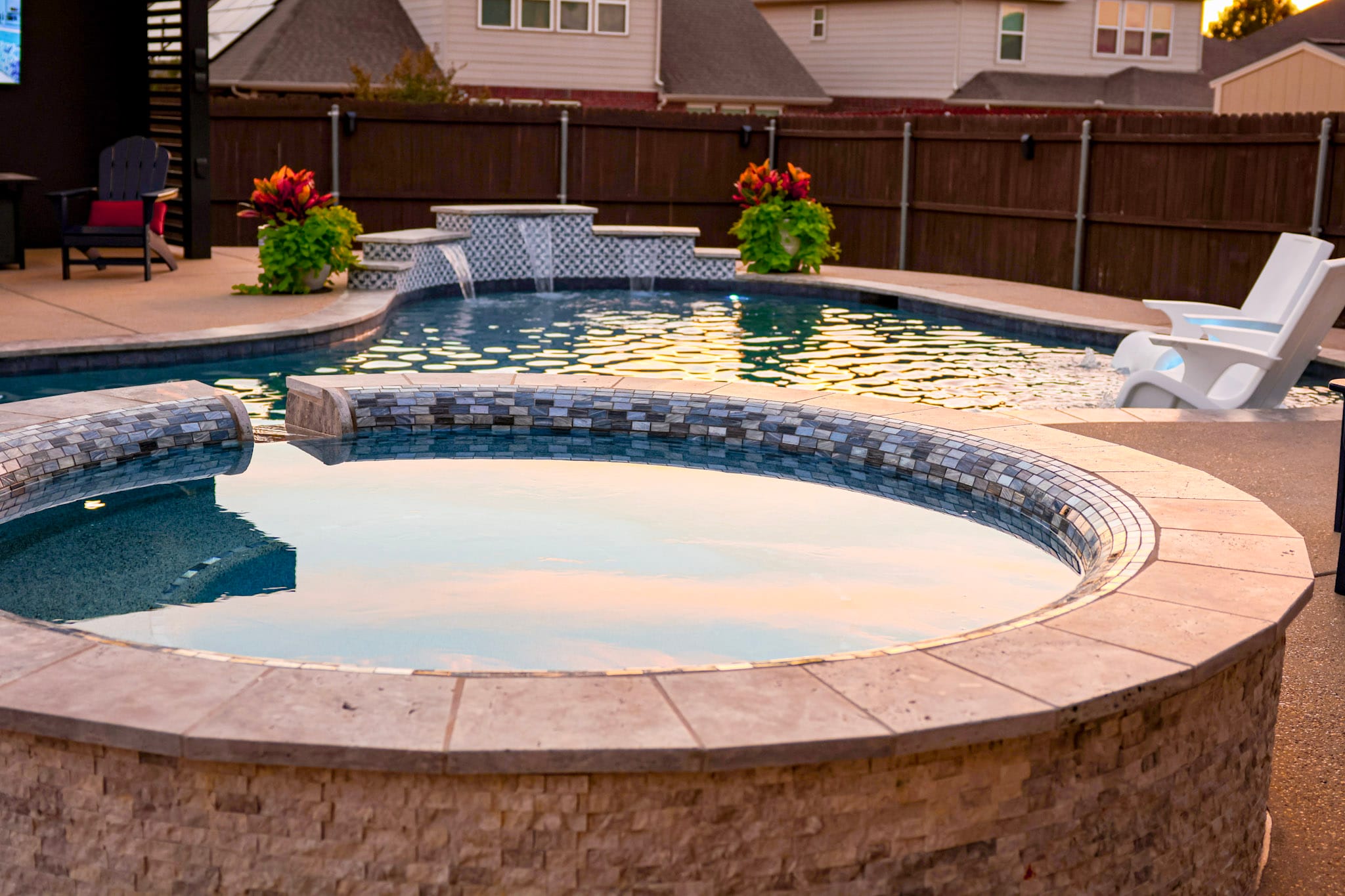 Raised circular spa with freeform pool and decorative water wall behind it