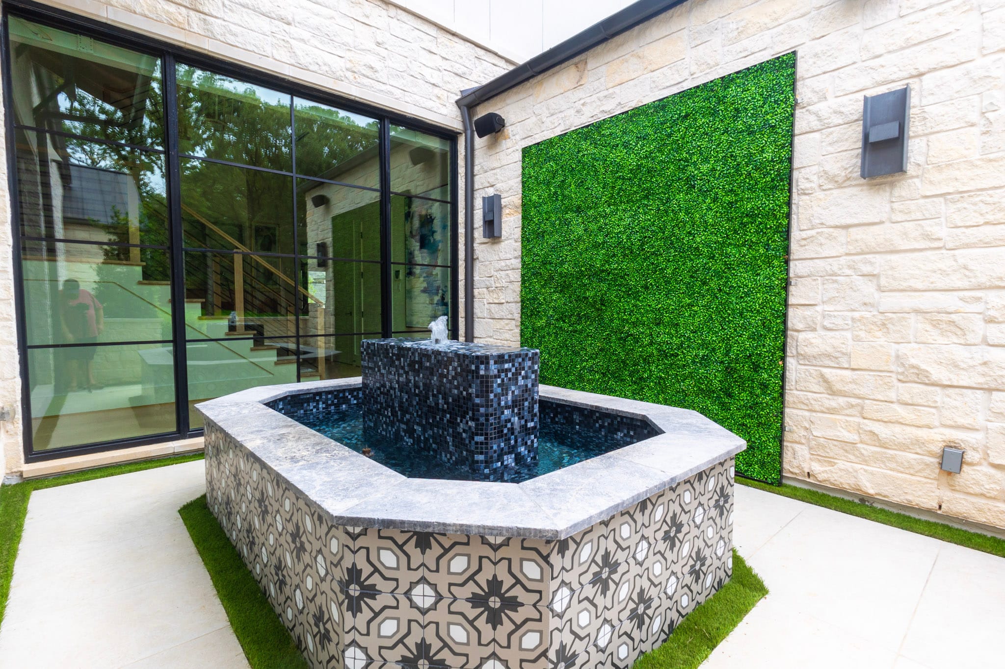 Patterned courtyard fountain beside green wall at Southlake residence