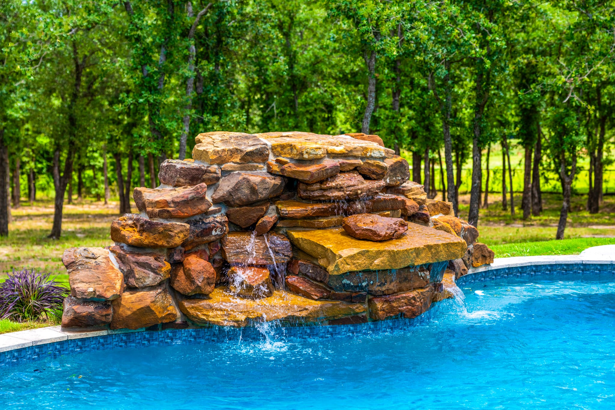 Rock waterfall feature flowing into residential swimming pool