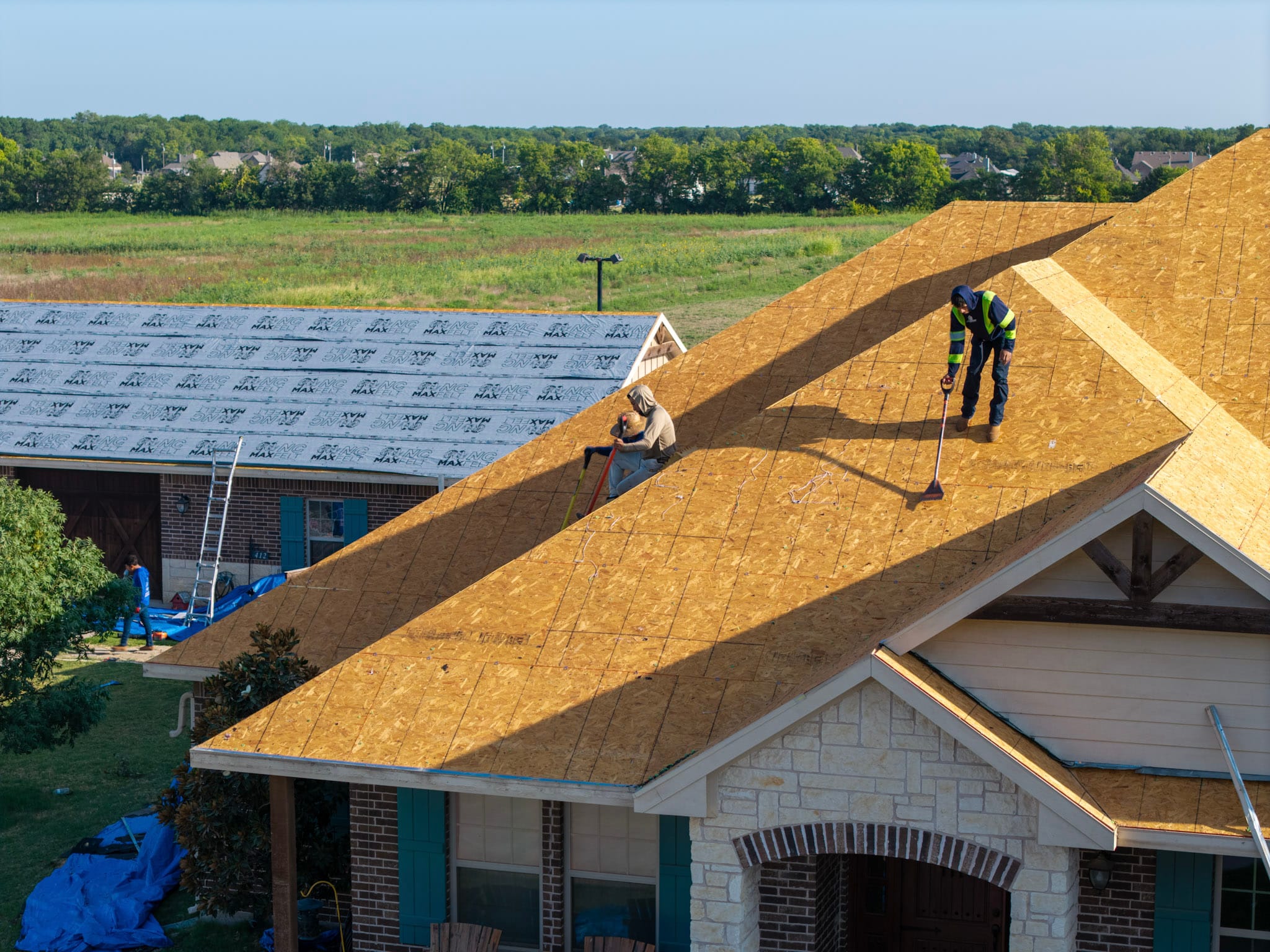 Overhead drone photograph of roofers working across exposed residential roof deck