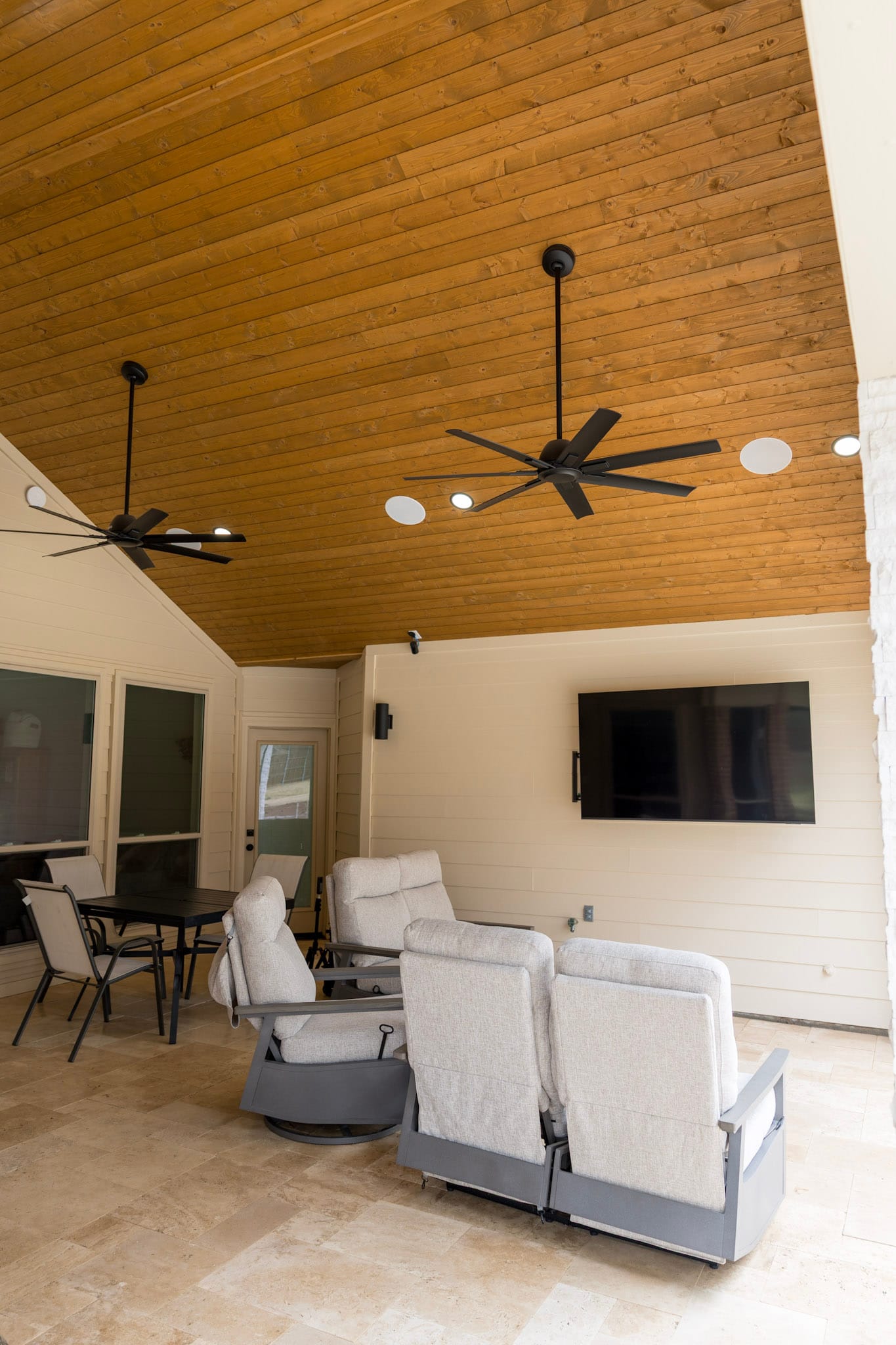 Covered patio with wood ceiling, ceiling fans, television, and seating