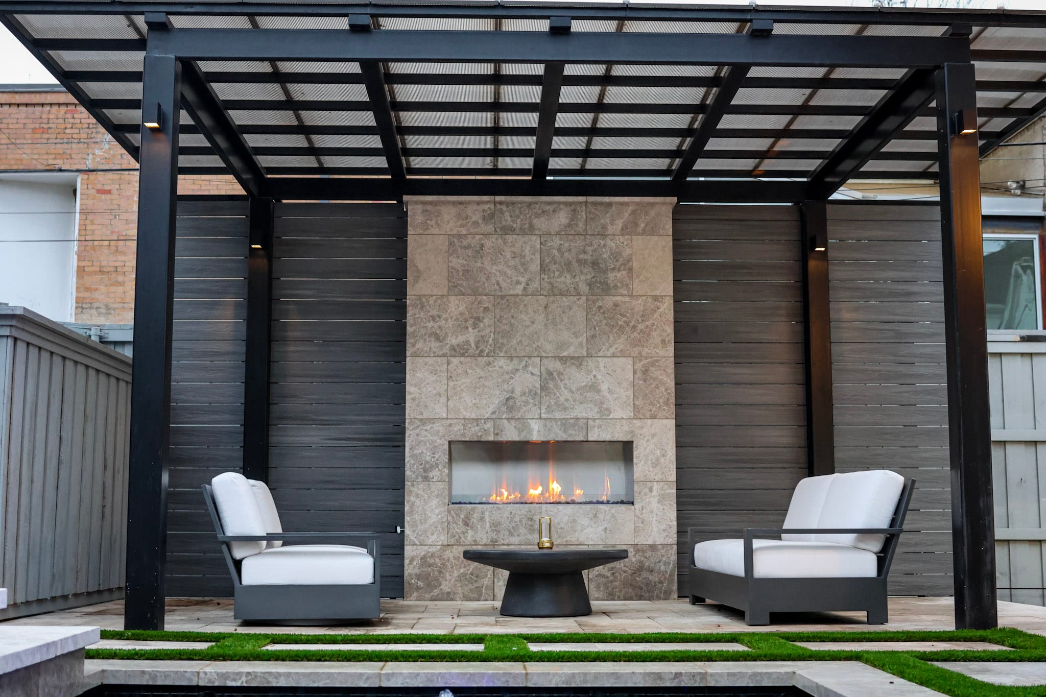 Covered patio with linear fireplace and white outdoor seating