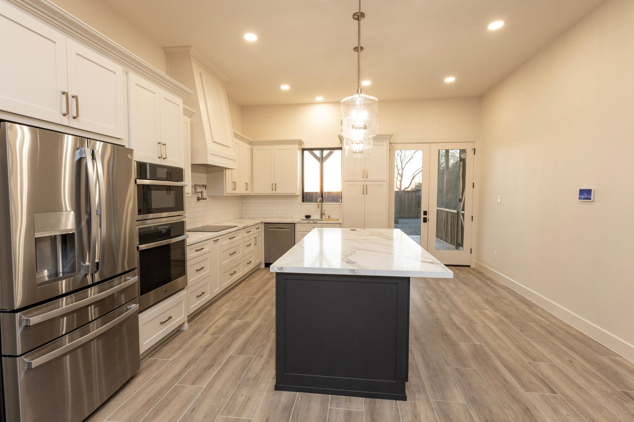 Modern white kitchen with dark island and stainless appliances in Celina barndominium