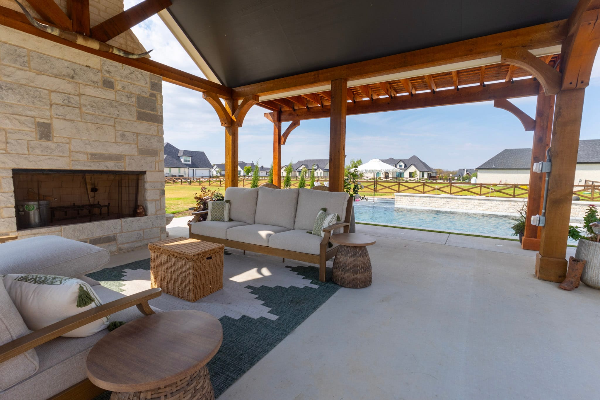 Existing covered patio with outdoor fireplace overlooking a swimming pool