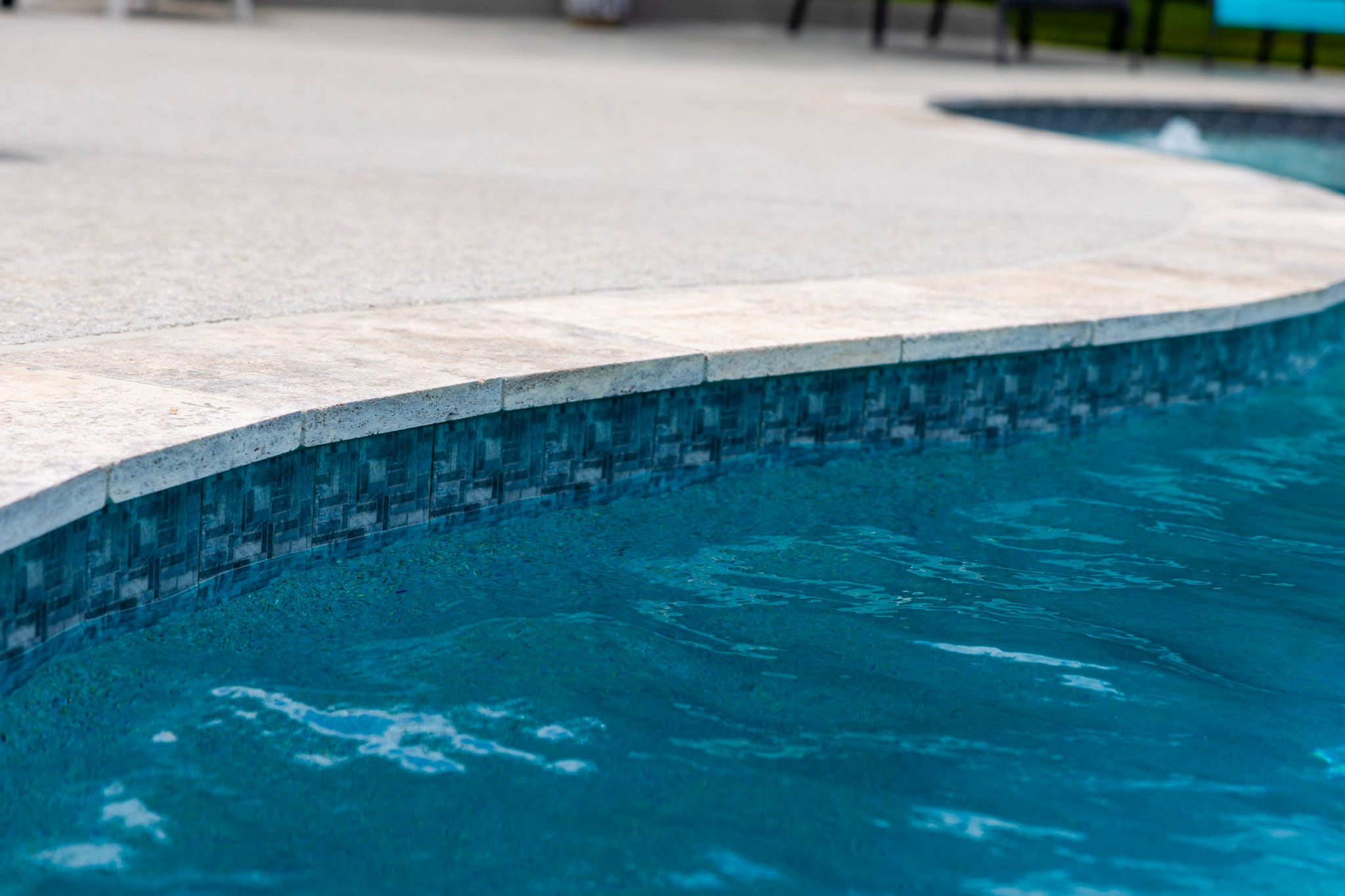 Close detail of pool coping and blue waterline tile in Weatherford