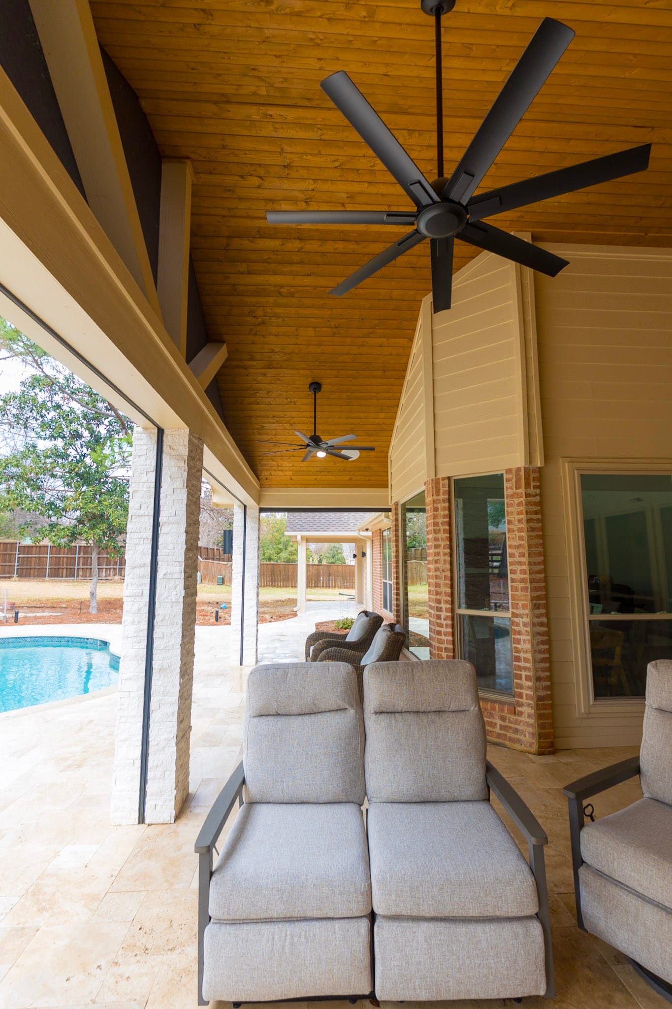 Covered patio with retractable screen tracks, ceiling fans, and seating