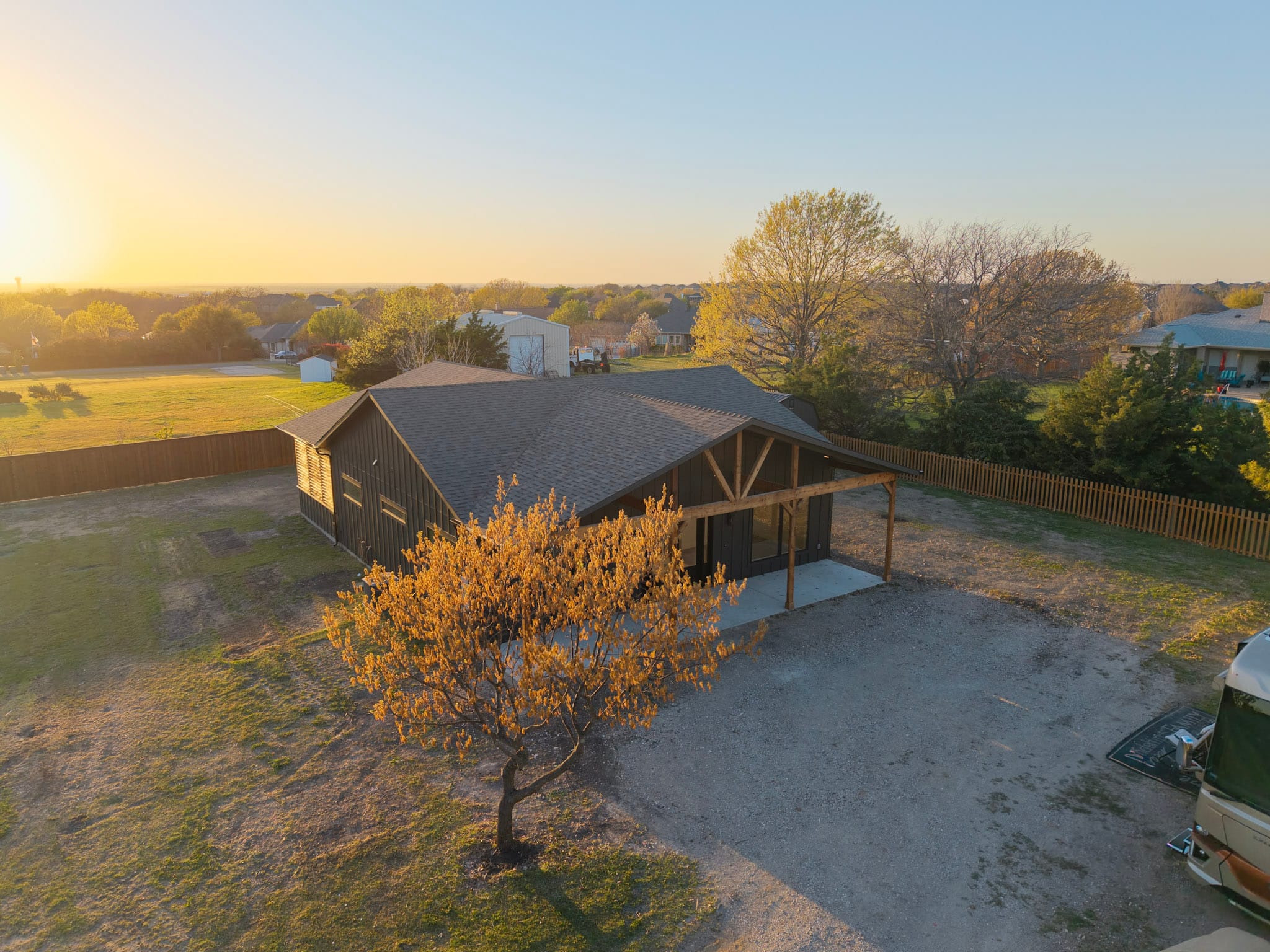 Aerial view of dark barndominium and surrounding residential property in Celina