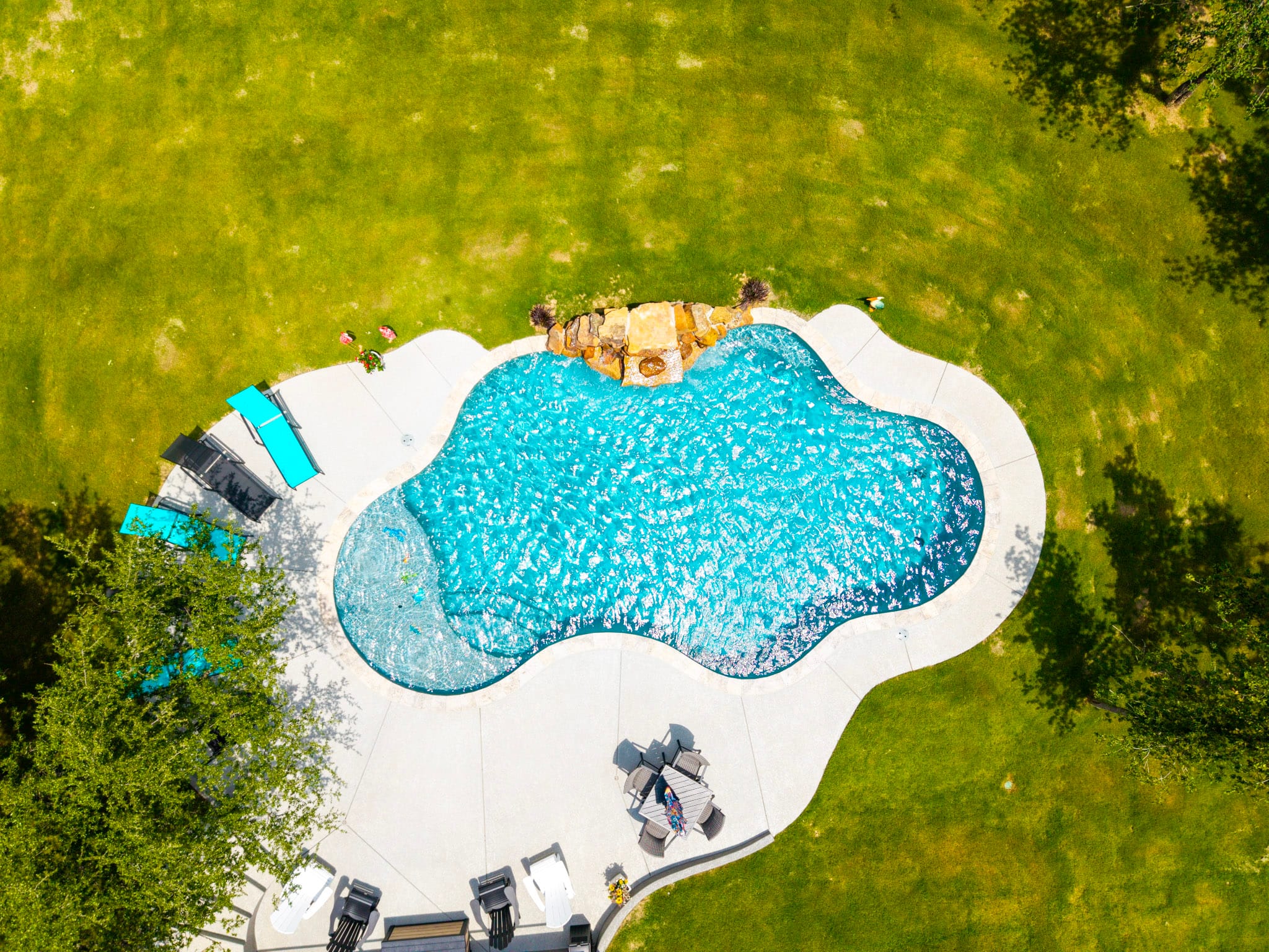 Top-down aerial view of freeform swimming pool and surrounding deck