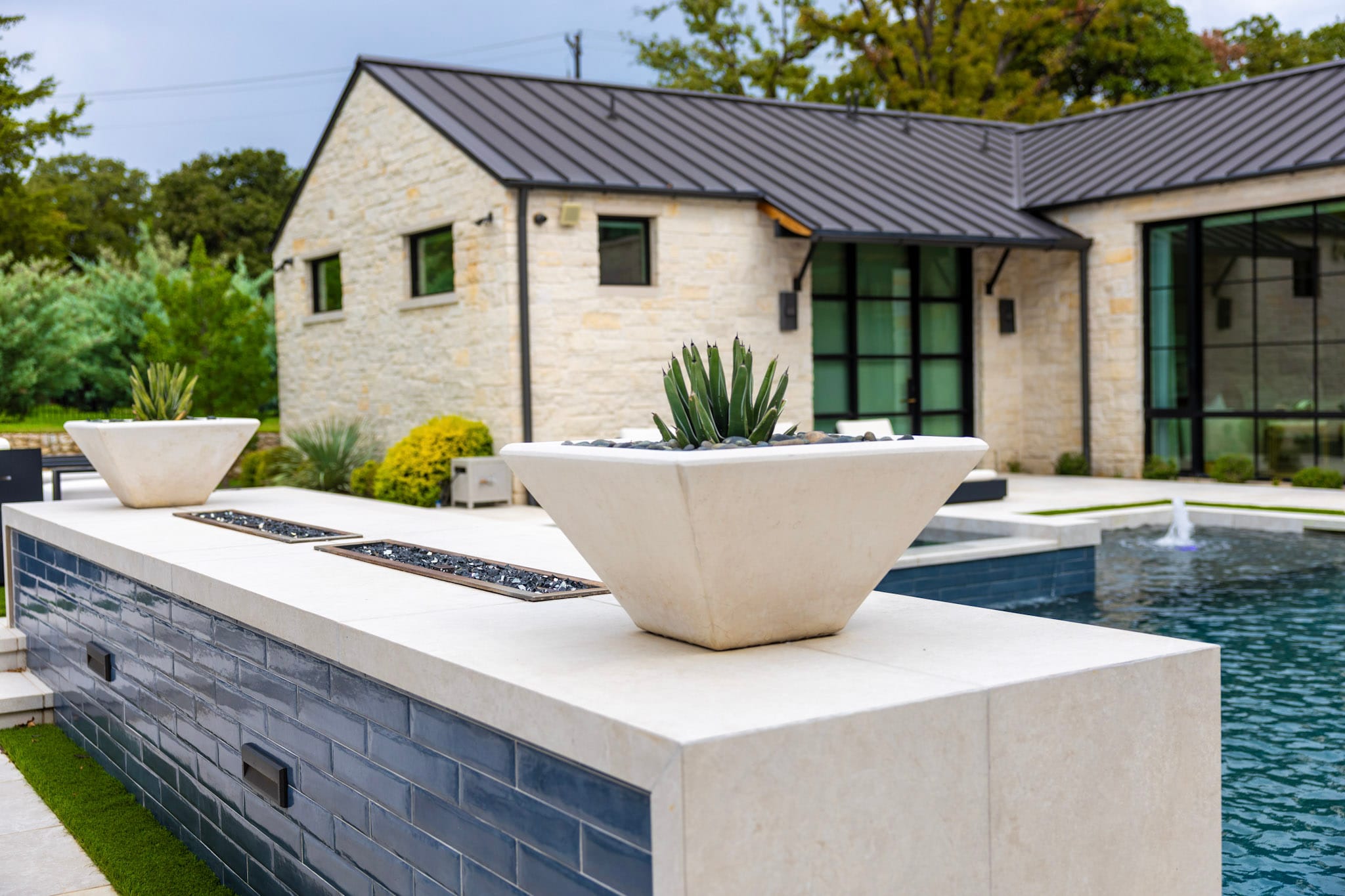 Raised blue-tile wall with porcelain top, planters and pool behind it