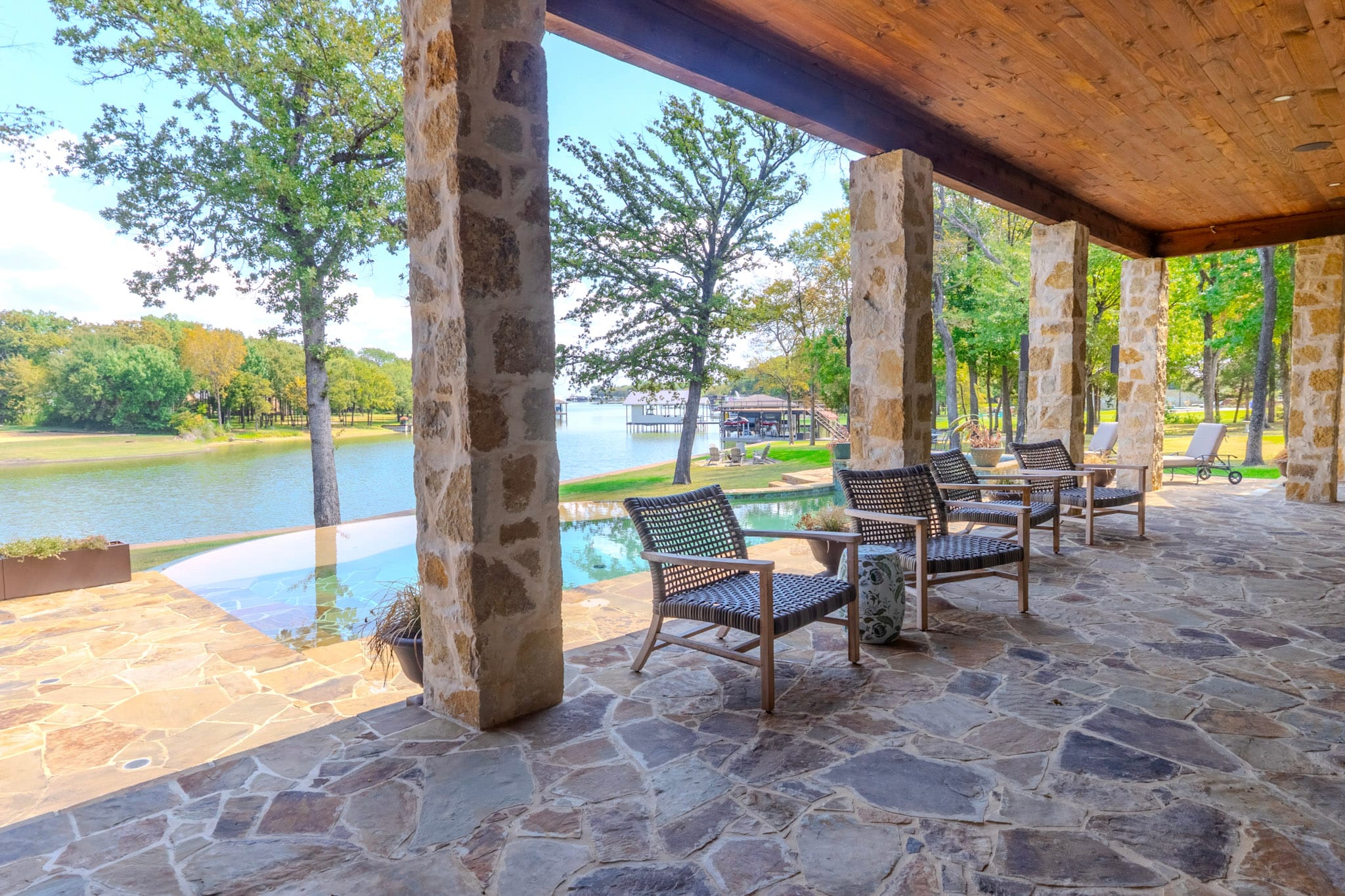 Covered patio seating with pool and reservoir visible between stone columns