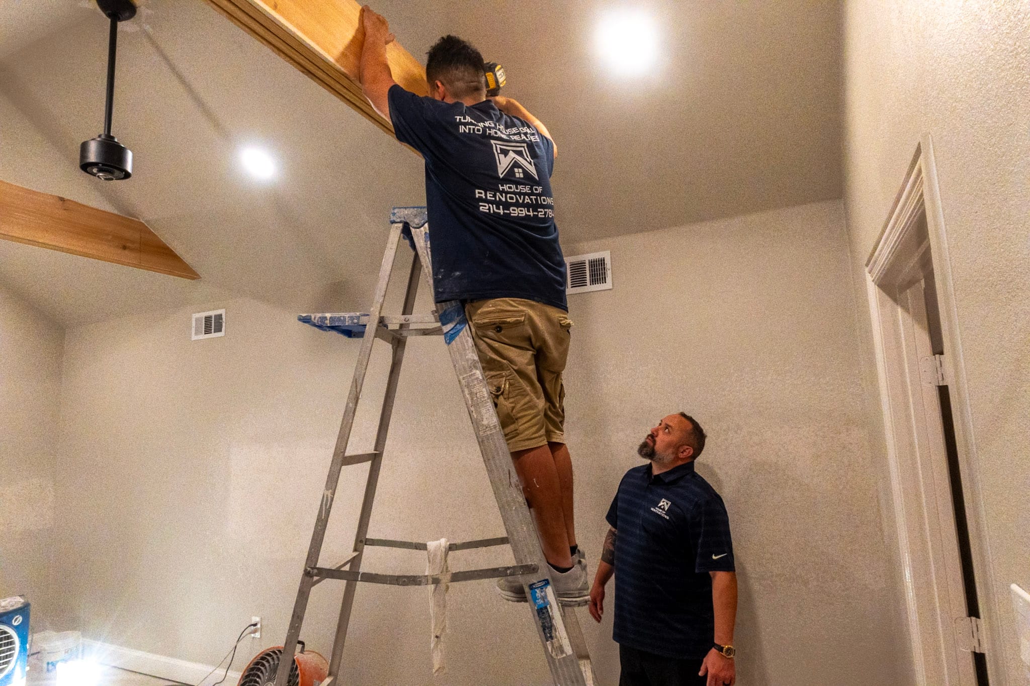 Attic addition under construction with wood ceiling beams, ladders and tools