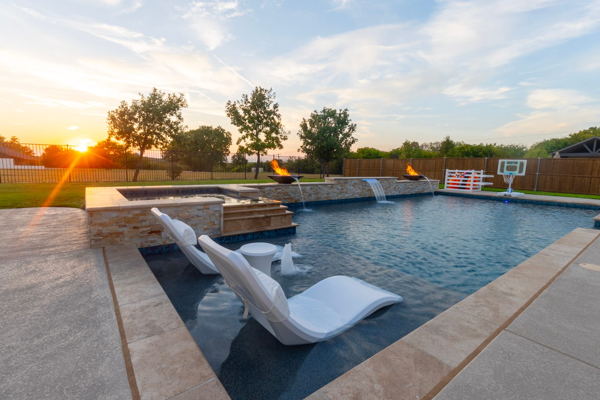 Wide sunset pool with spa fire bowls water features and loungers