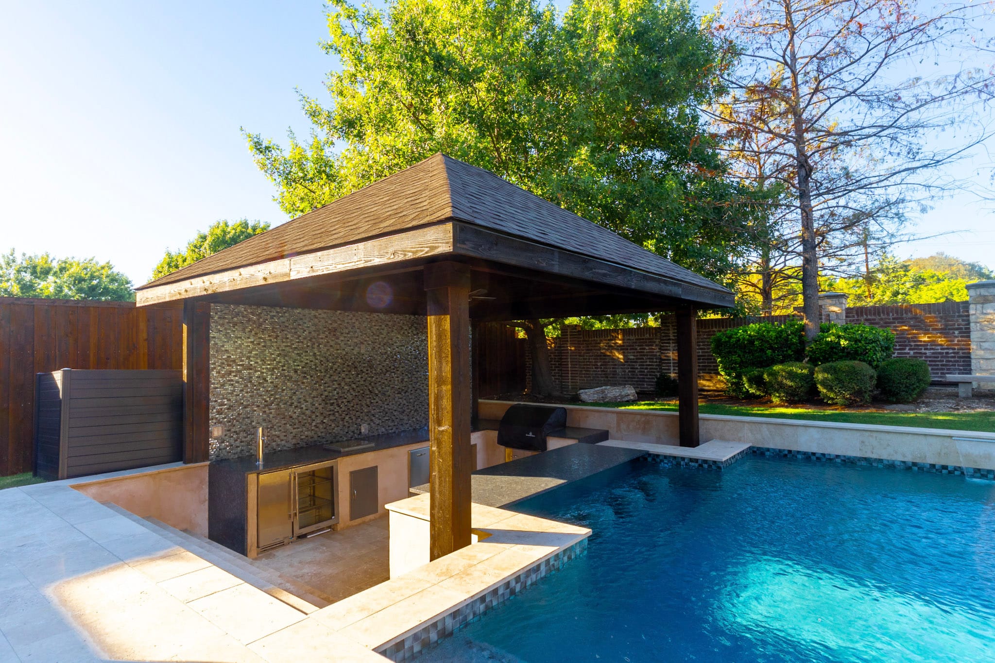 Covered sunken outdoor kitchen beside swimming pool in Allen Texas