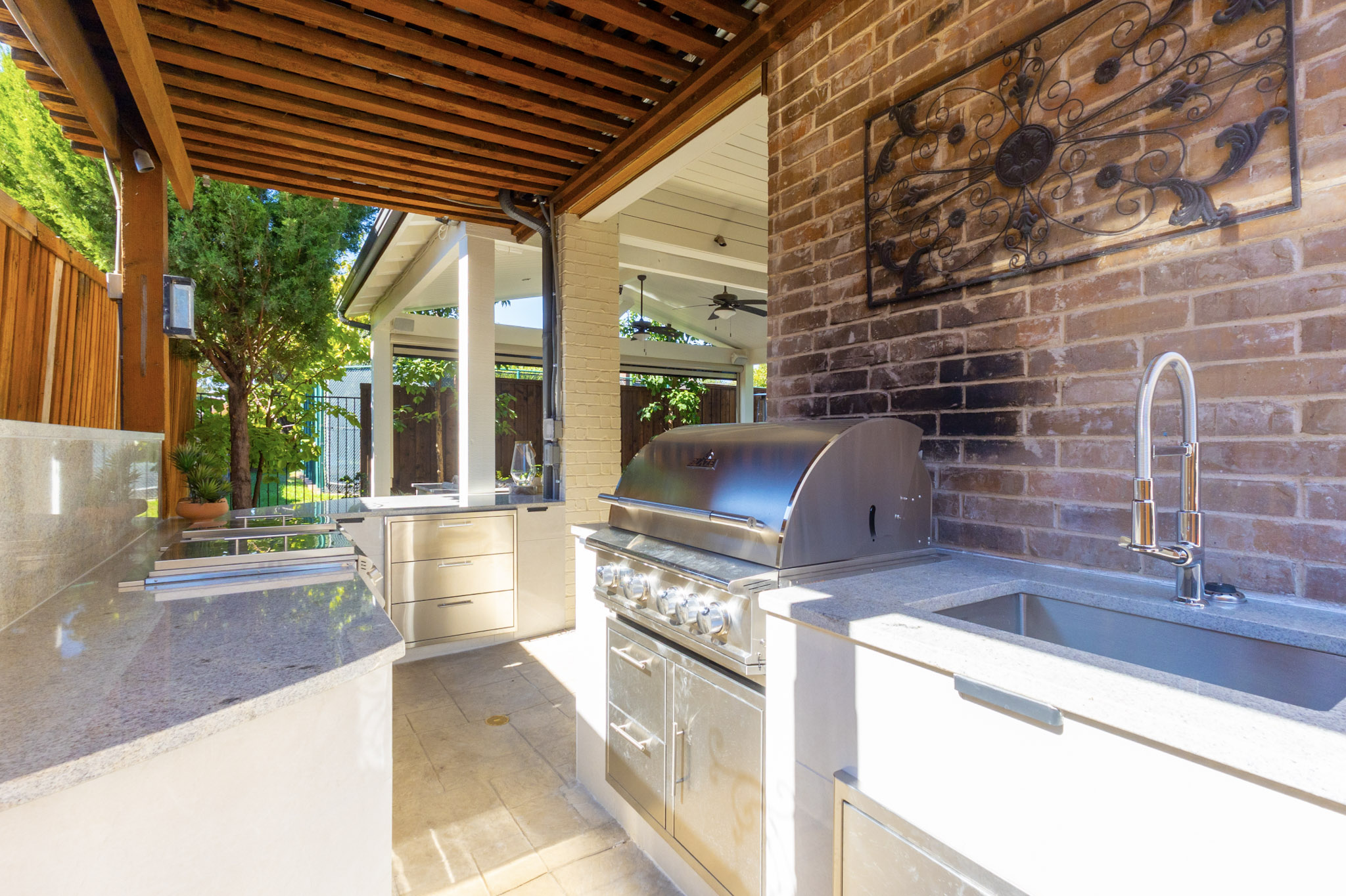 Covered outdoor kitchen with built-in grill, sink, and countertops