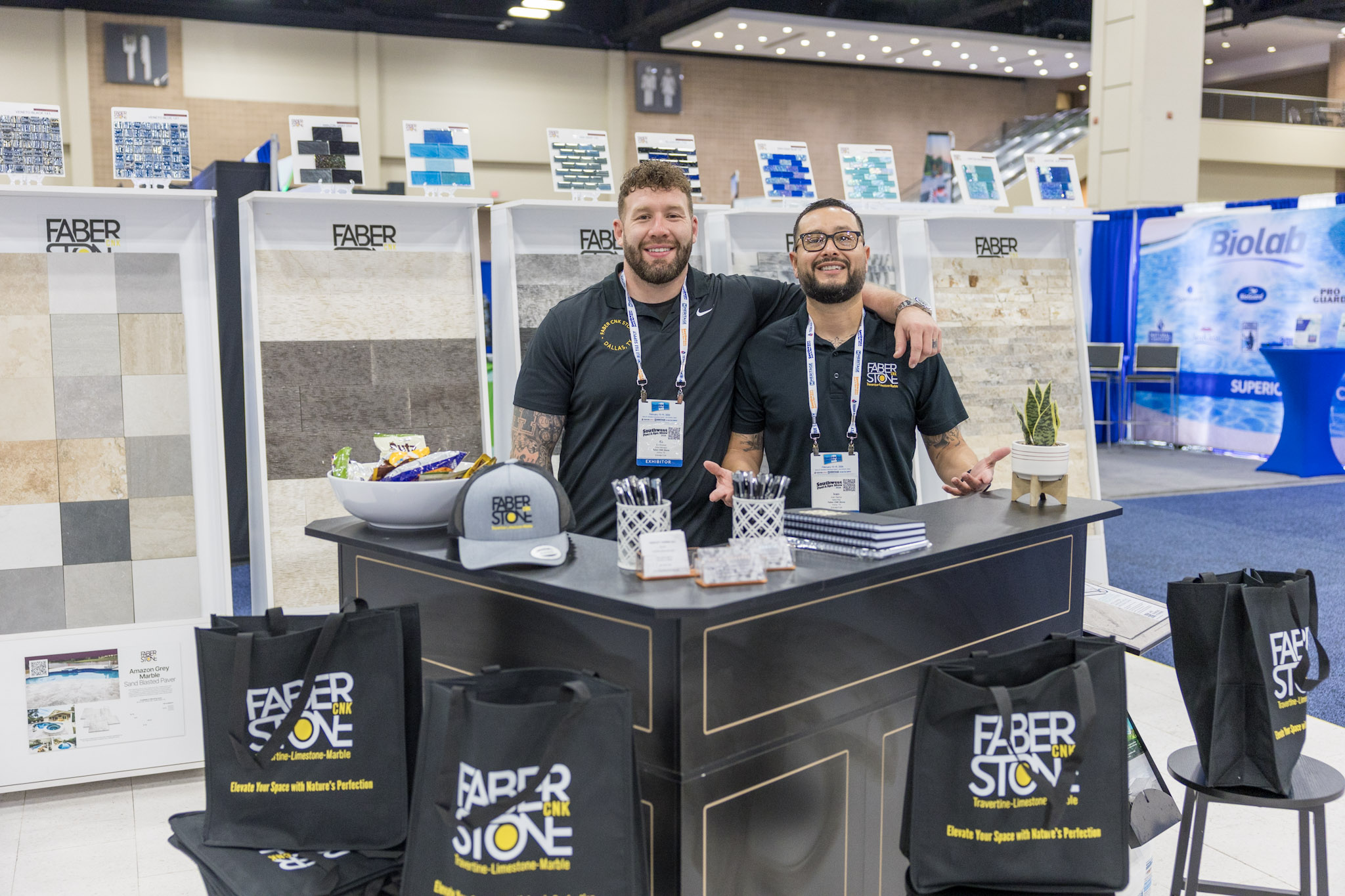 Two Faber CNK Stone representatives standing together inside trade show booth