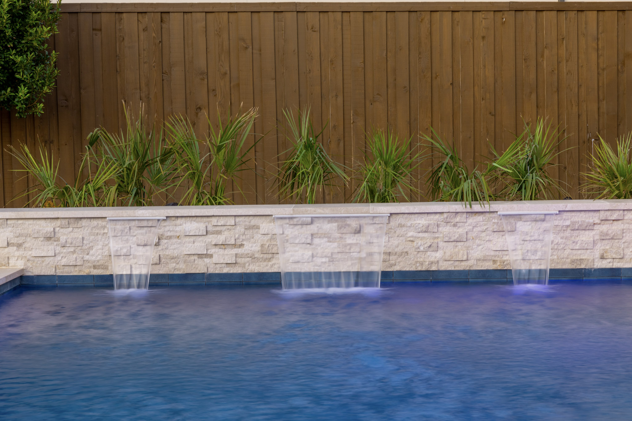 Three sheer descents flowing into blue pool water