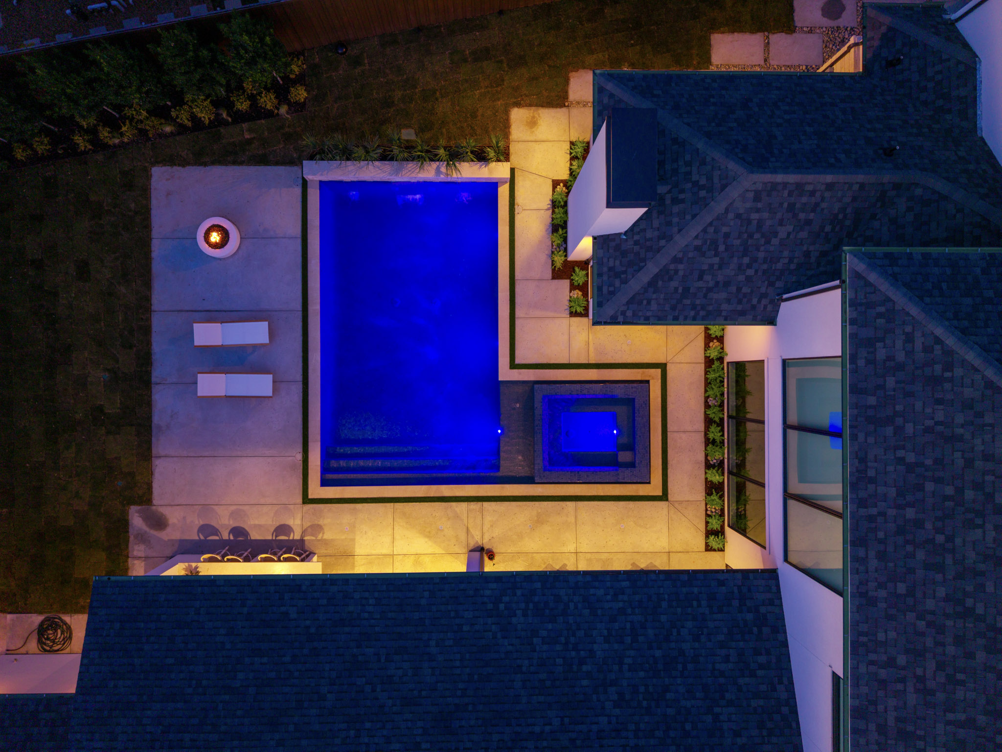 Nighttime aerial view of illuminated pool spa and fire feature