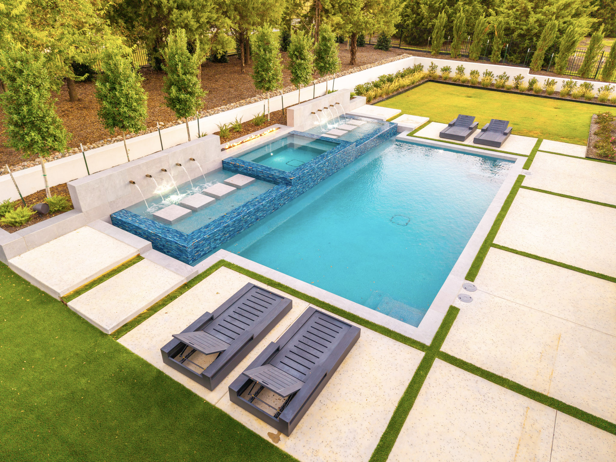 Angled drone view of modern pool spa water features and backyard
