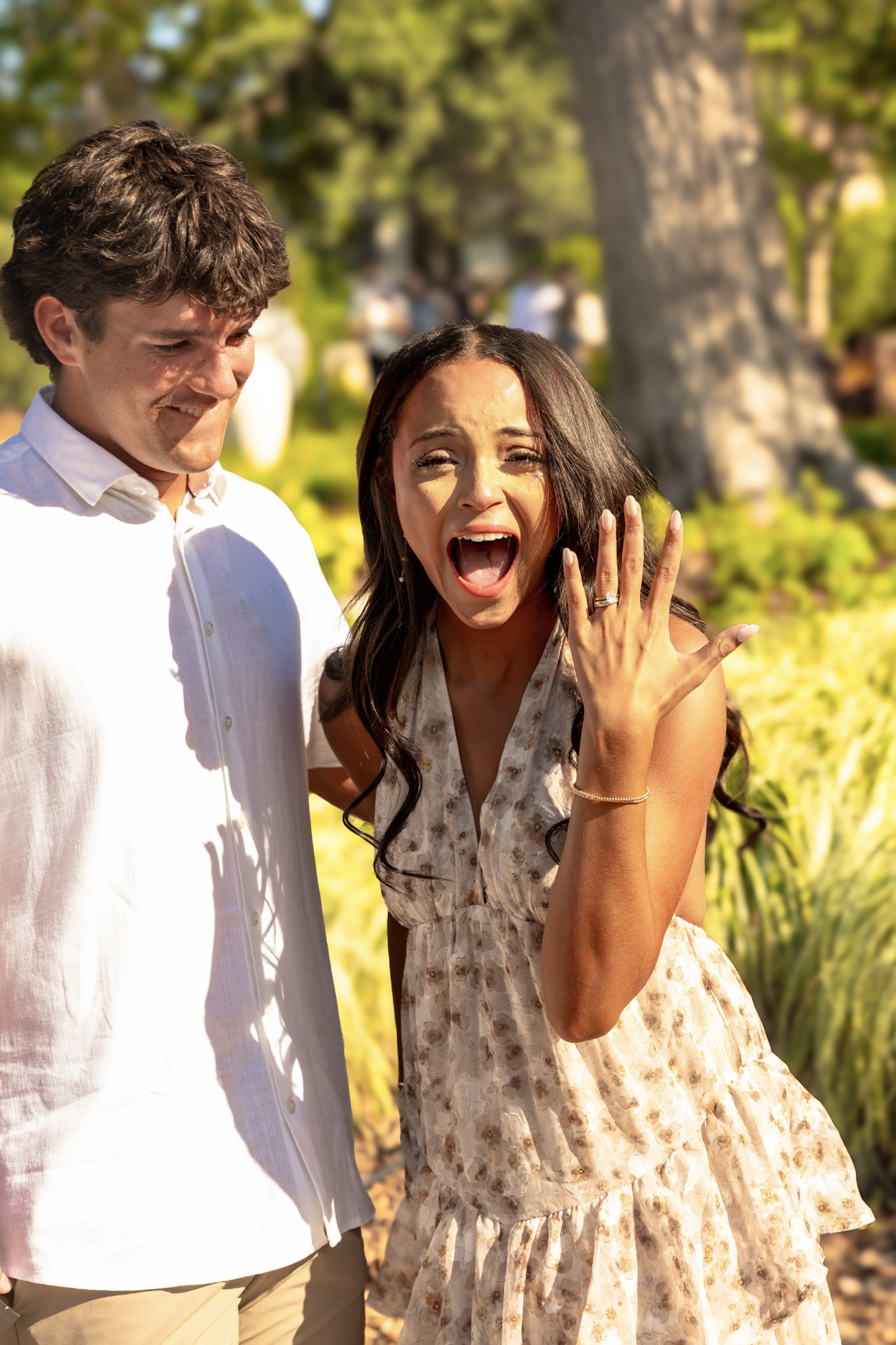 Excited woman holding up her engagement ring beside her fiancé