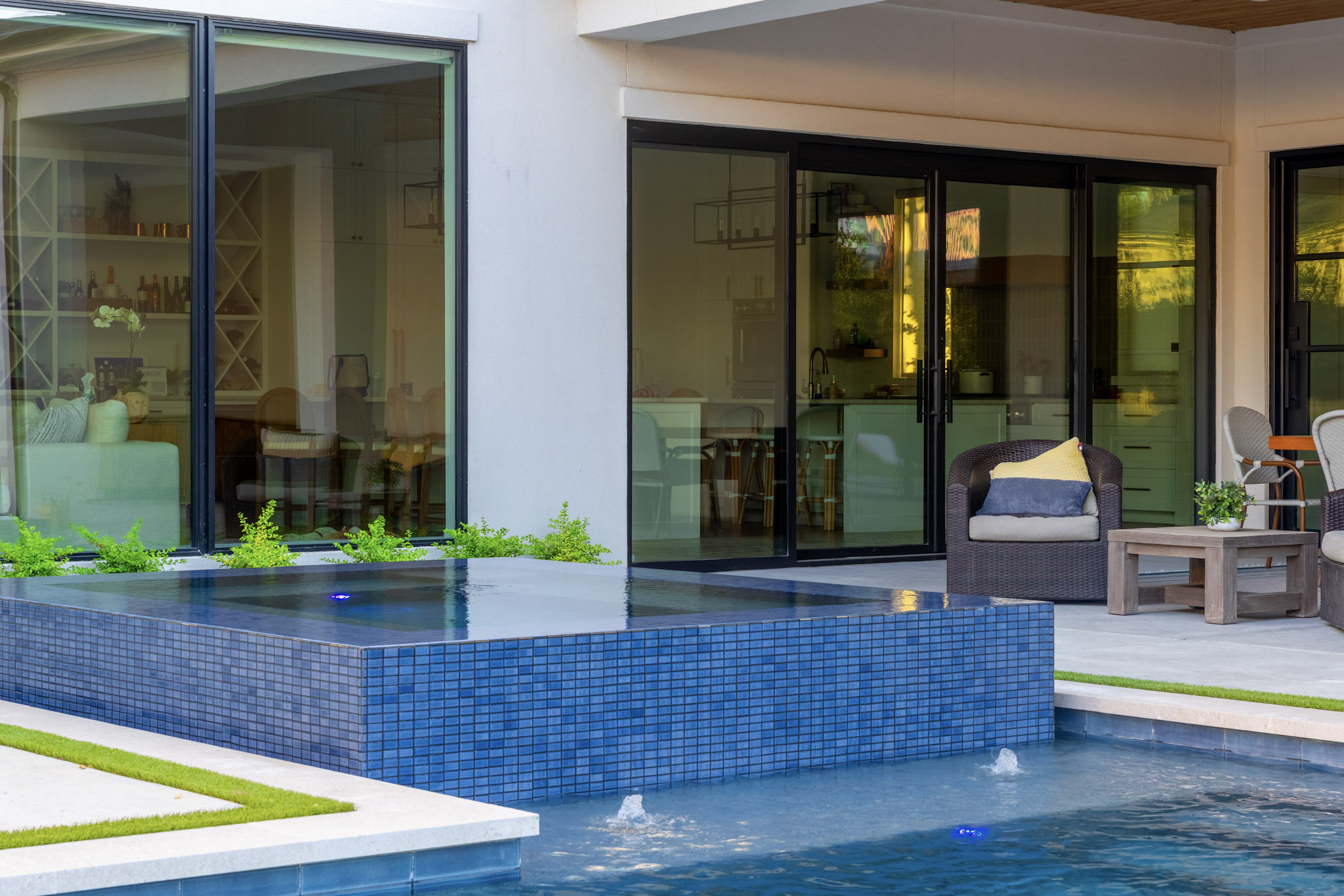 Raised spa in front of covered patio seating and sliding doors