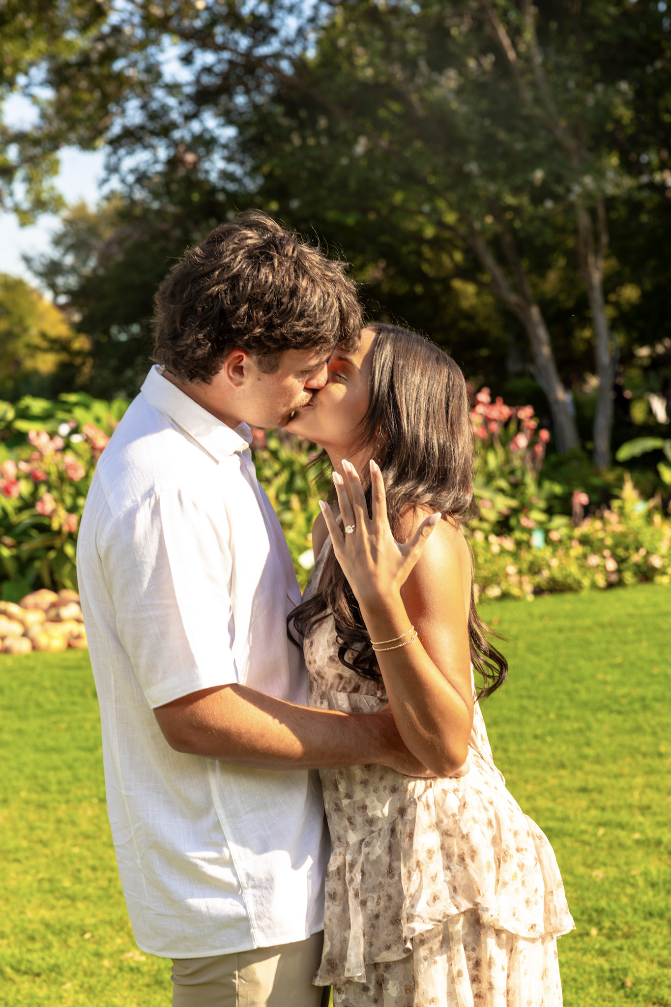 Engaged couple kissing while the woman displays her engagement ring